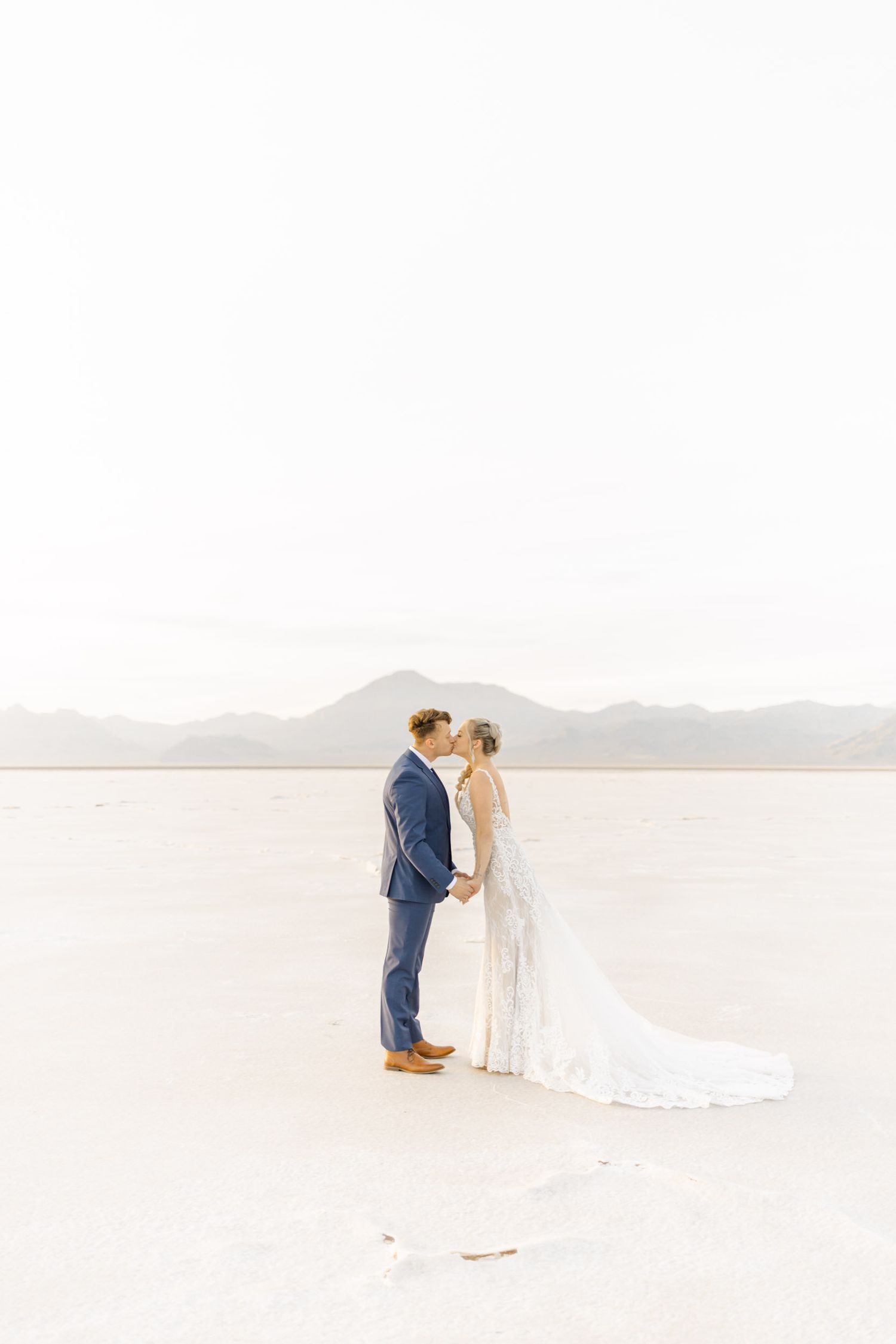 Bride and groom share a romantic moment on scenic salt flats during sunset.