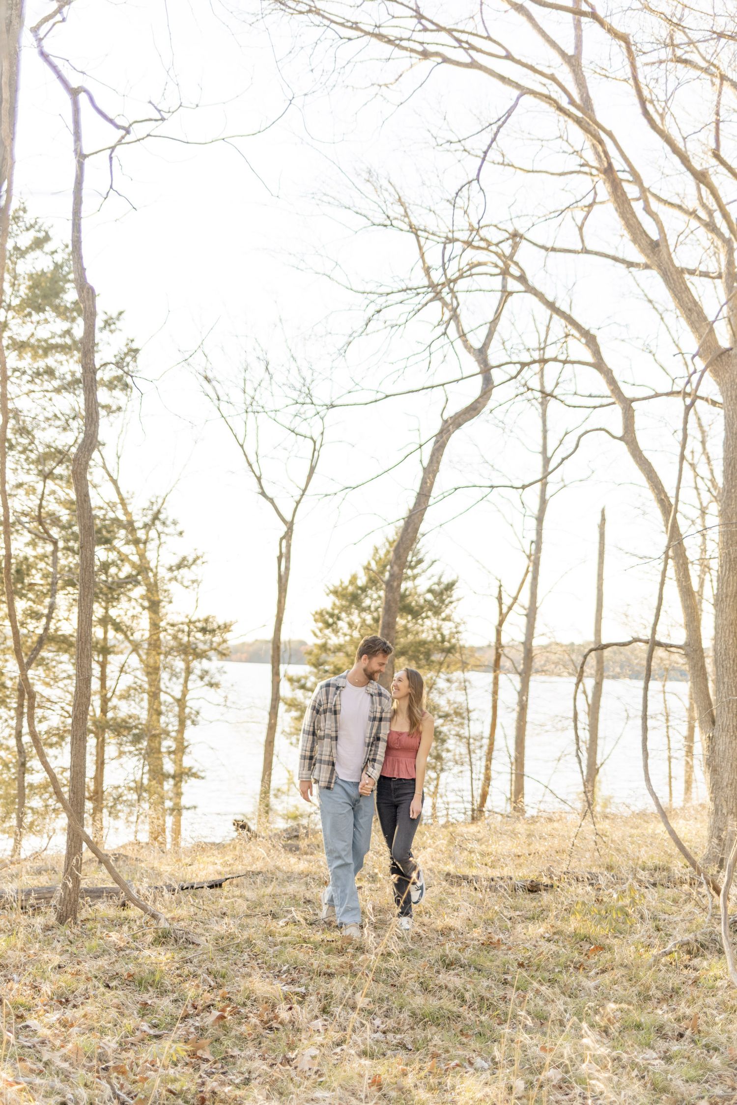 Distant silhouette of a couple walking among bare trees in winter landscape making a light, airy, creamy photo in Raleigh, North Carolina.