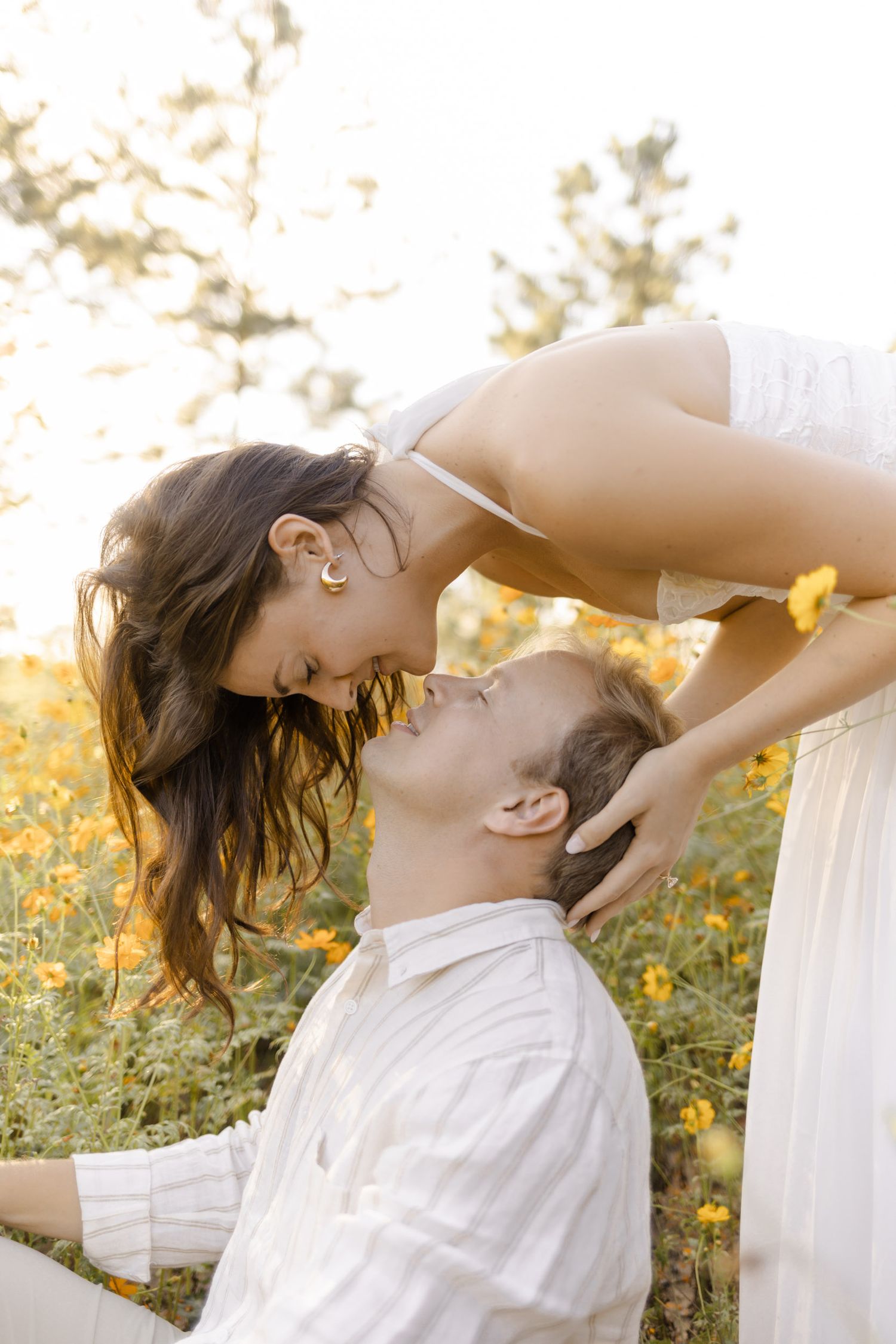 Playful romantic poses captured in a wildflower field during a sunset photoshoot for engagement photoshoot in Chapel Hill, NC.