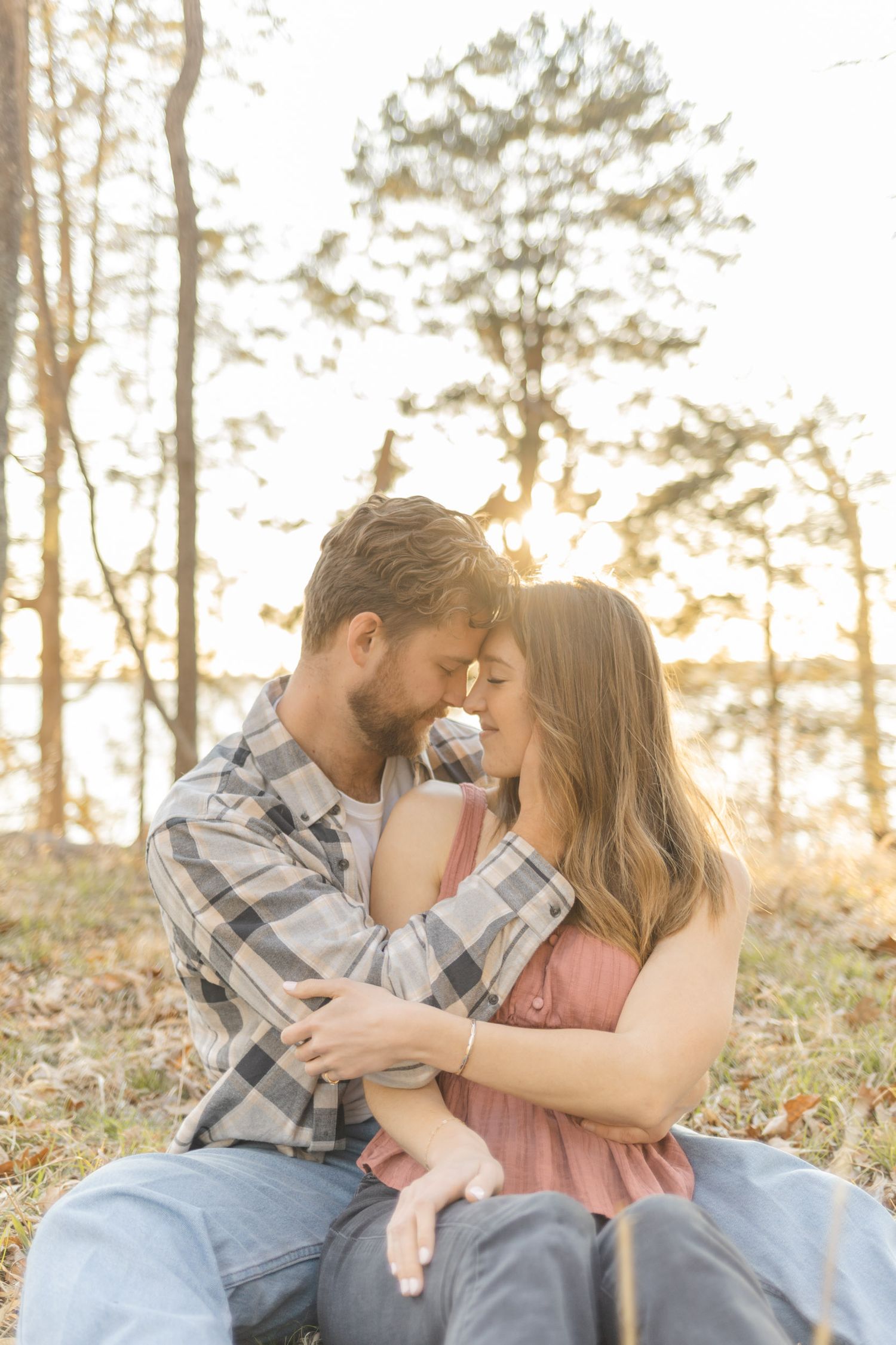 An intimate moment shared between a couple in a sunlit forest setting during their couples lifestyle photoshoot in Raleigh, North Carolina.