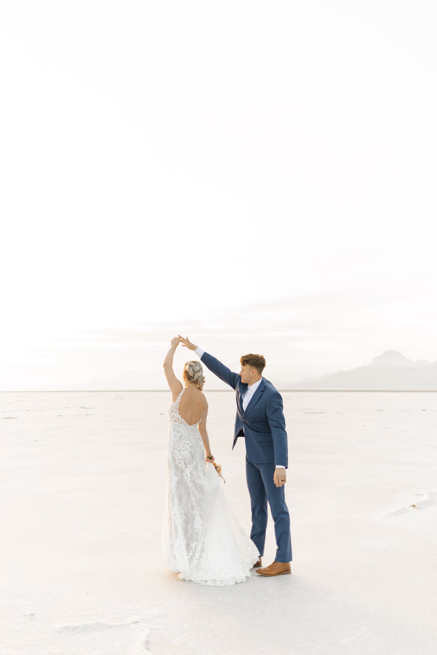 Newlyweds share a romantic dance on the stark white landscape of a salt flat.