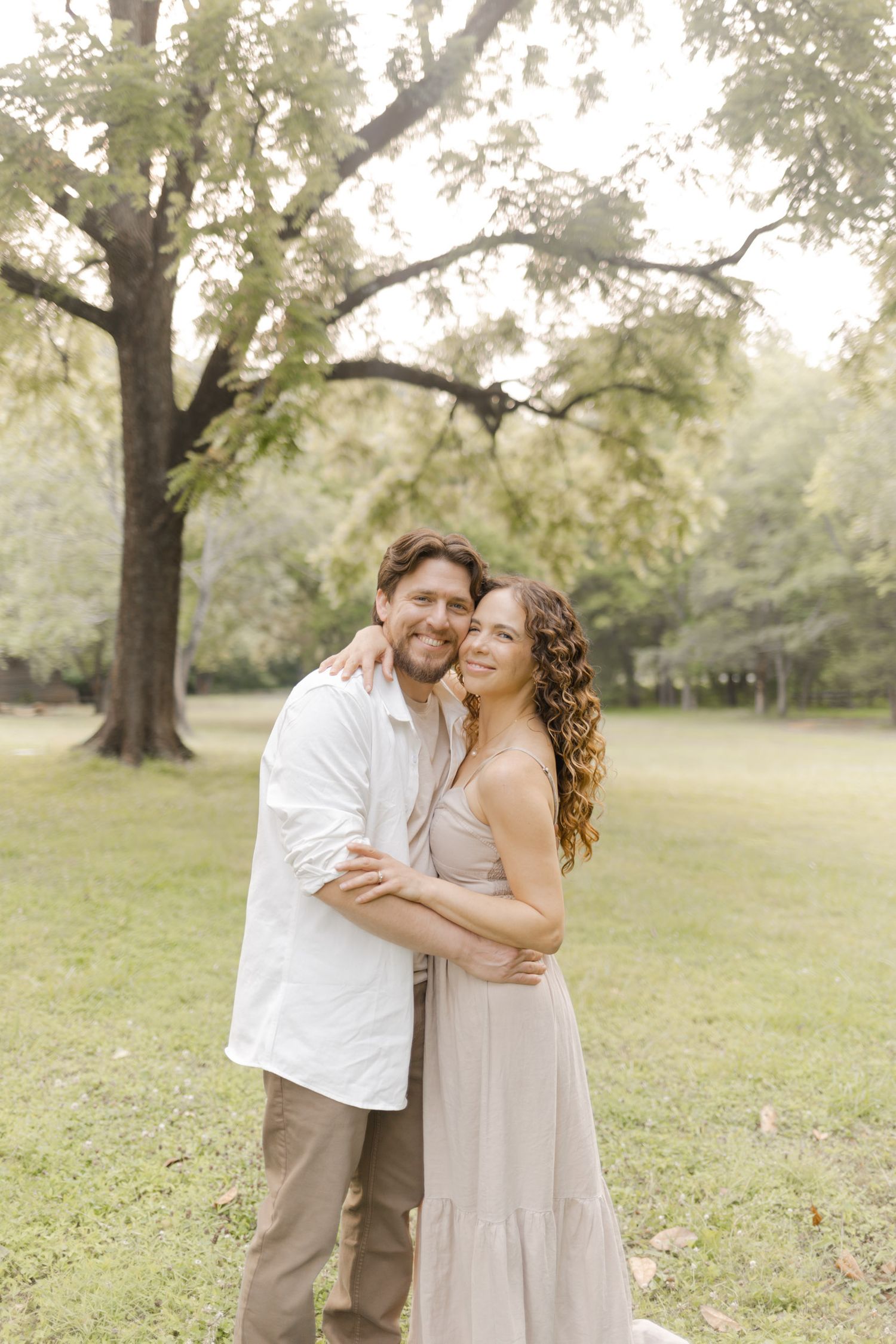 Couple in neutral tones shares loving embraces in a sunlit outdoor setting during photoshoot with Kinsley Nicole Photography.