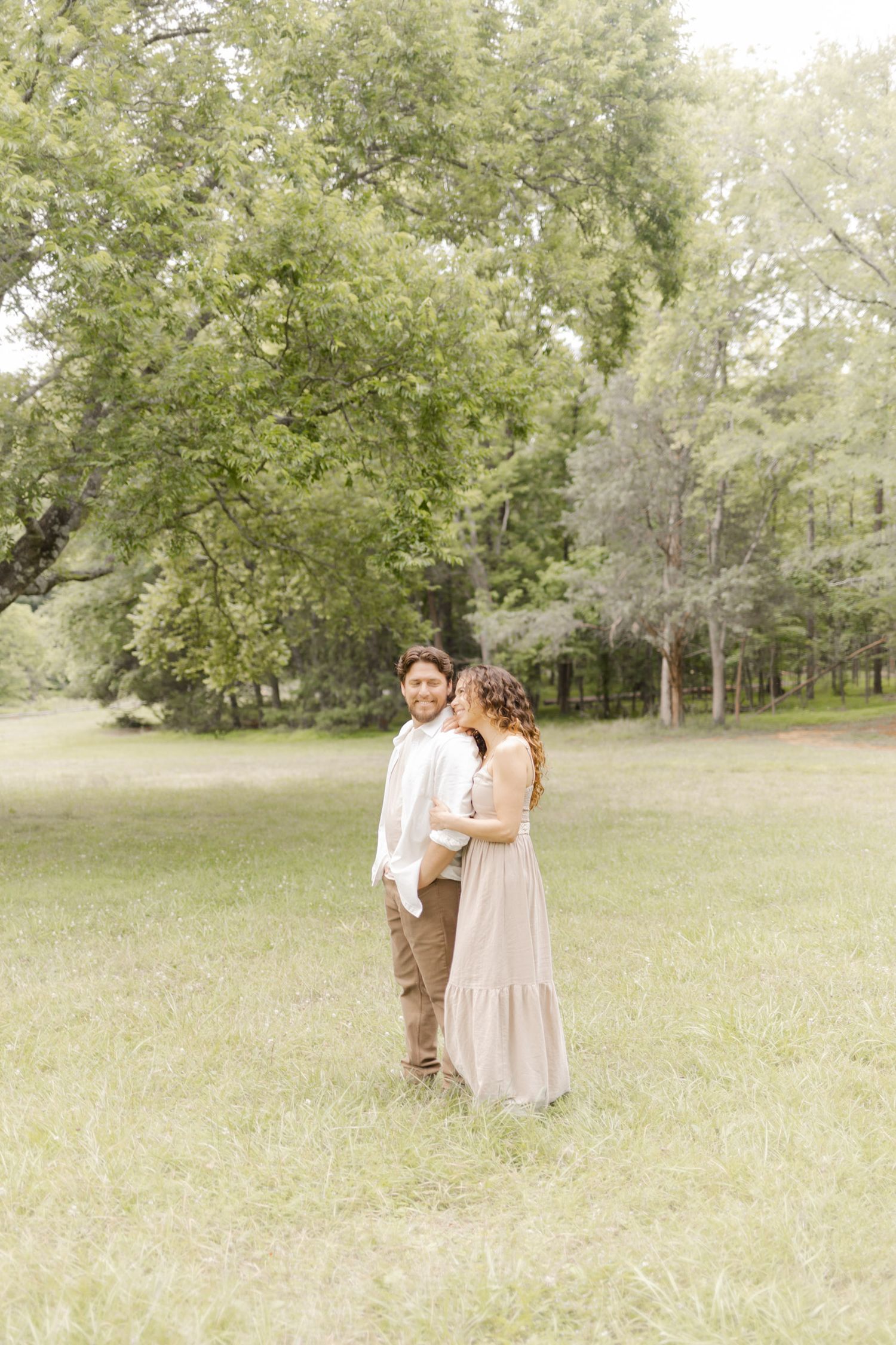 A pair in coordinating outfits embrace while walking through a sun-drenched park setting in Durham, North Carolina.