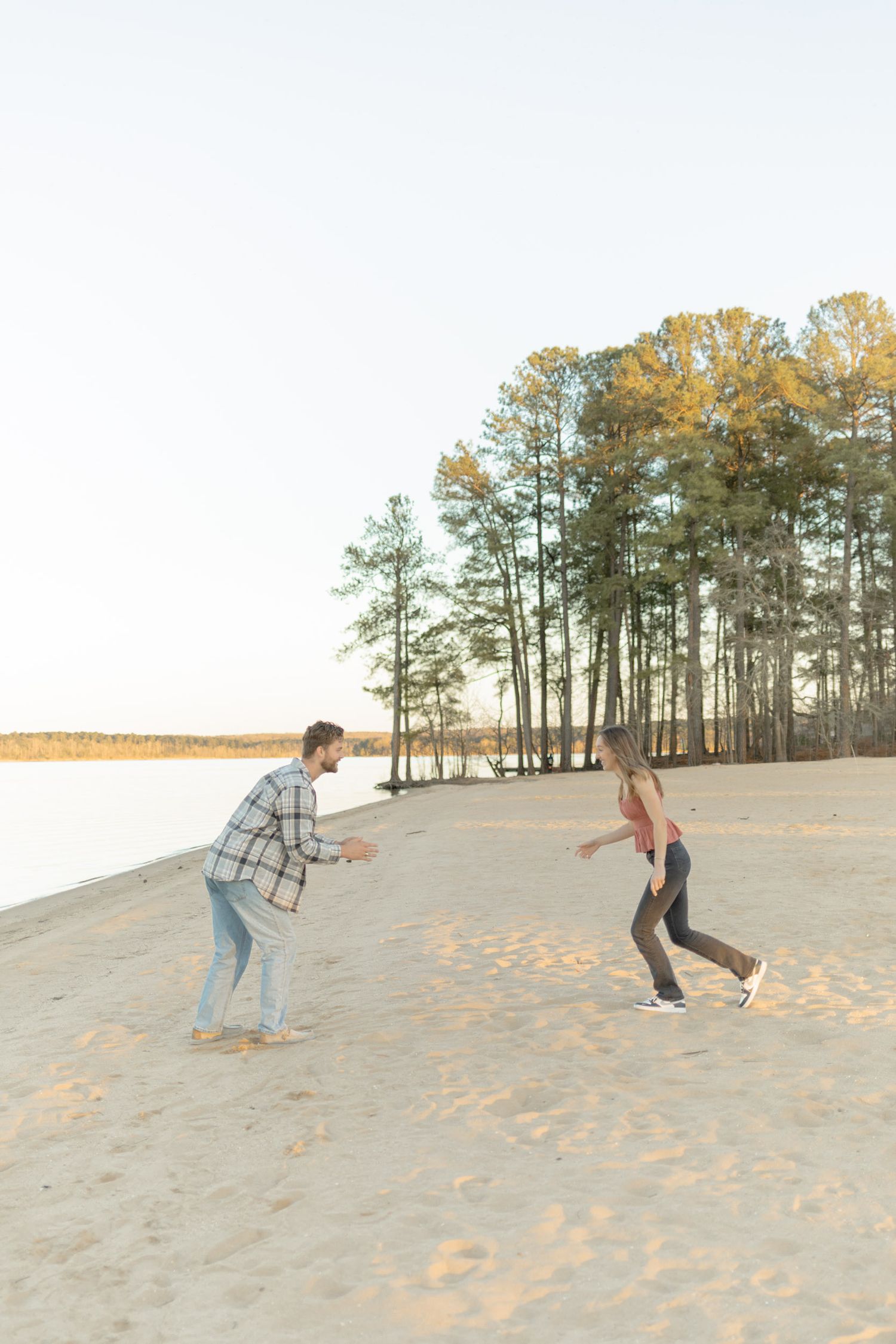 Couple playing and running on sandy dunes during a beach photoshoot in Raleigh, North Carolina.