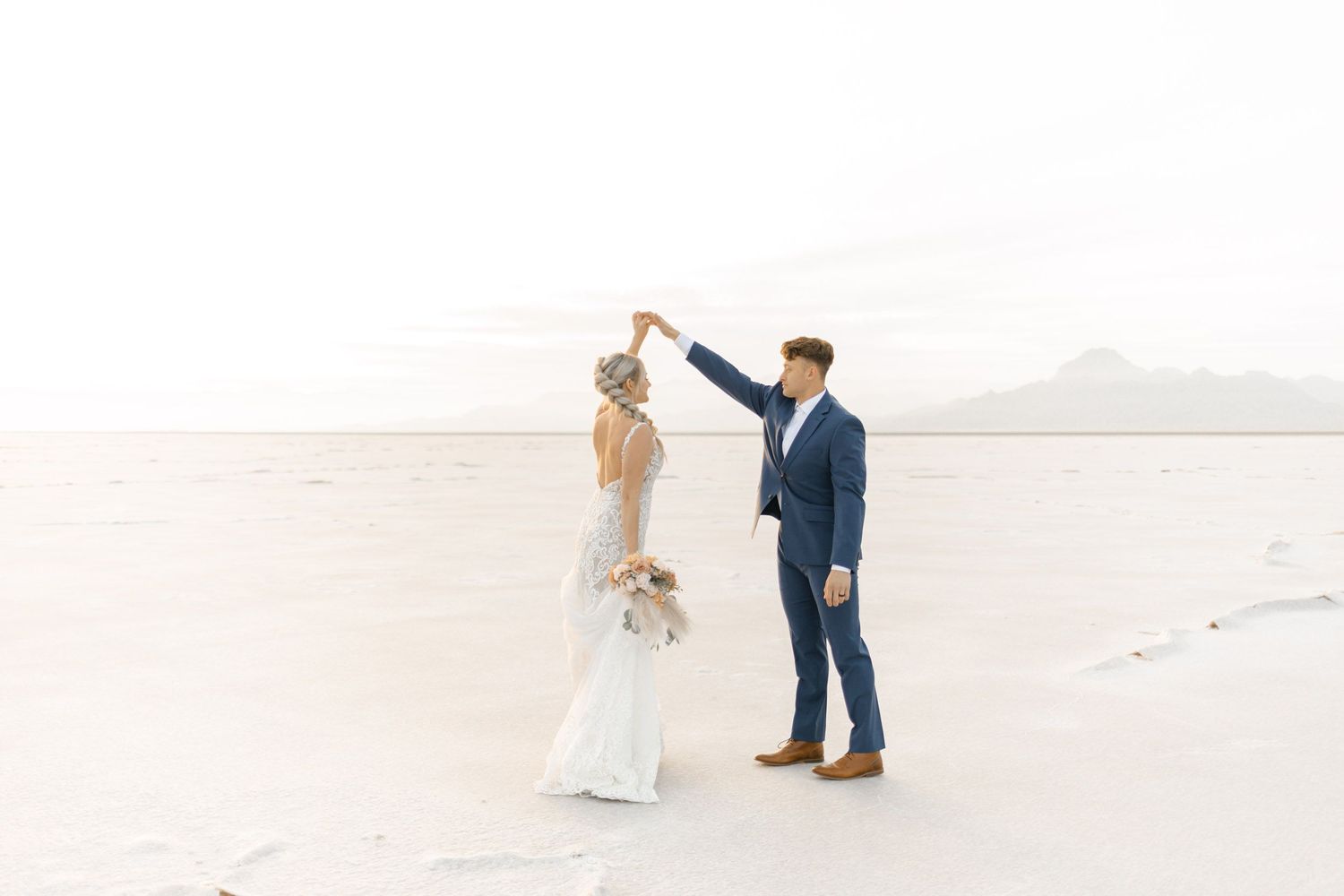 Wedding couple posing together on pristine white sand beach with ocean view.