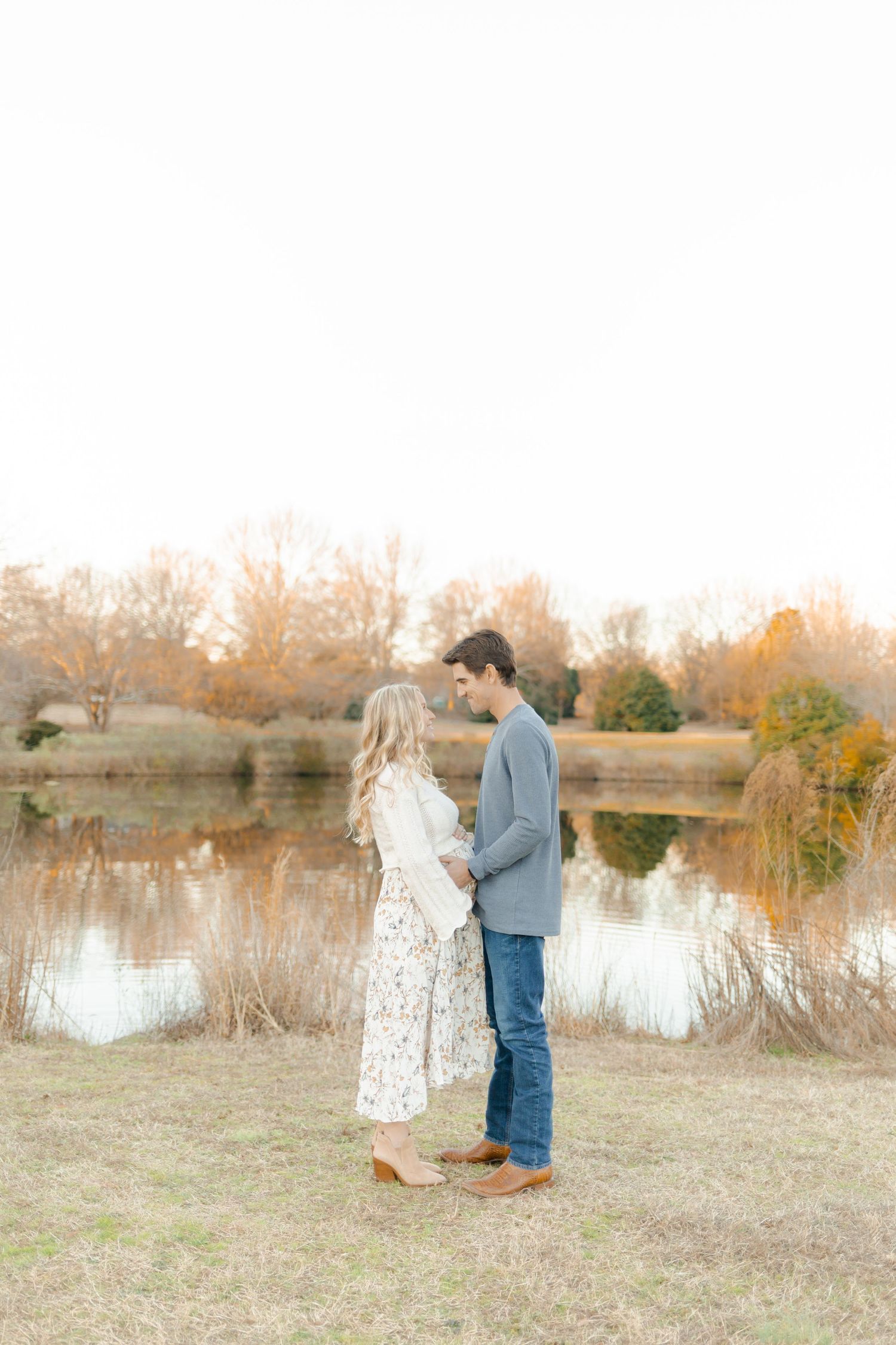 A couple shares a romantic moment by a lake during an autumn engagement photoshoot.