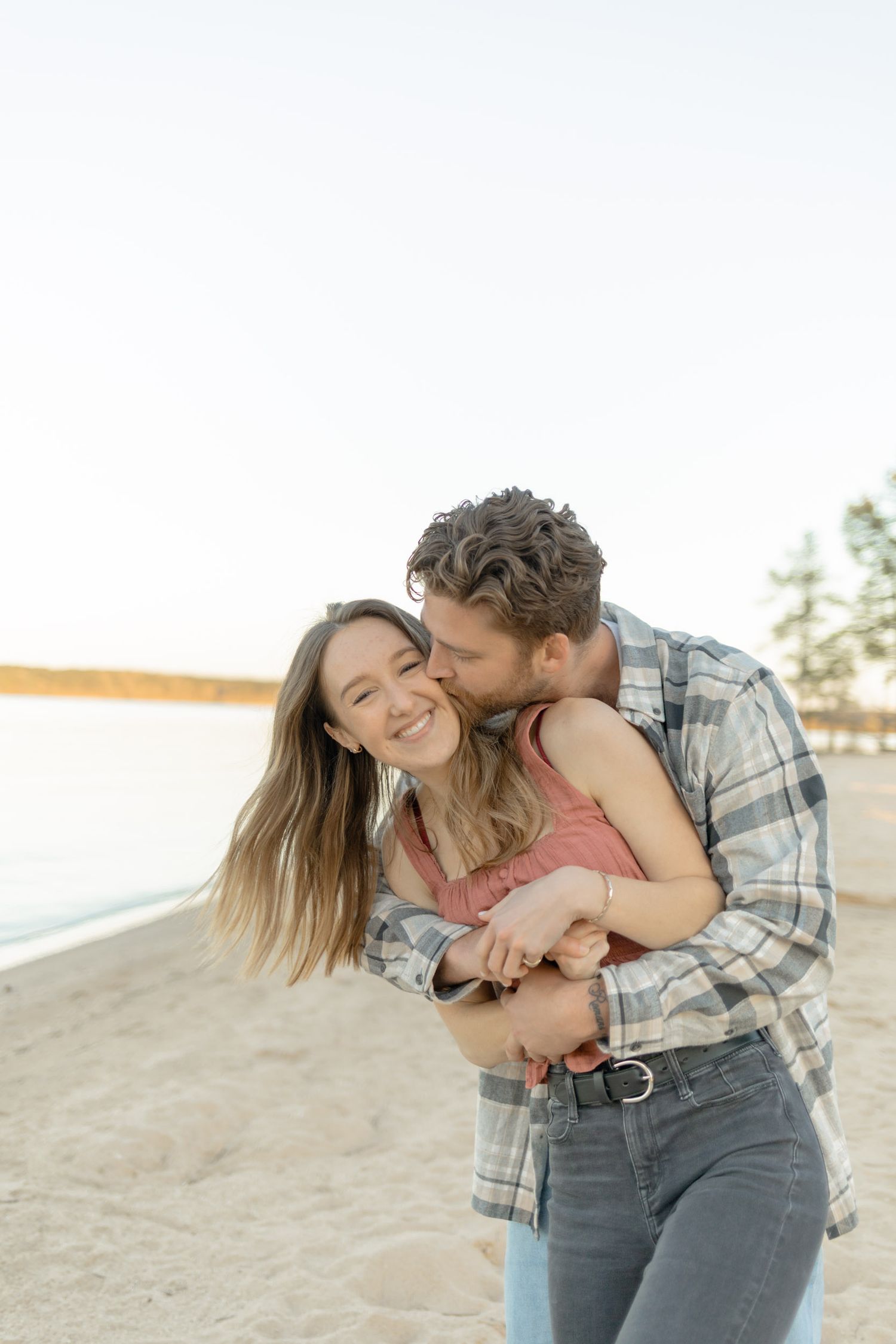 A tender moment between a couple laughing on a beach at sunset during their couples lifestyle photoshoot in Raleigh, North Carolina.