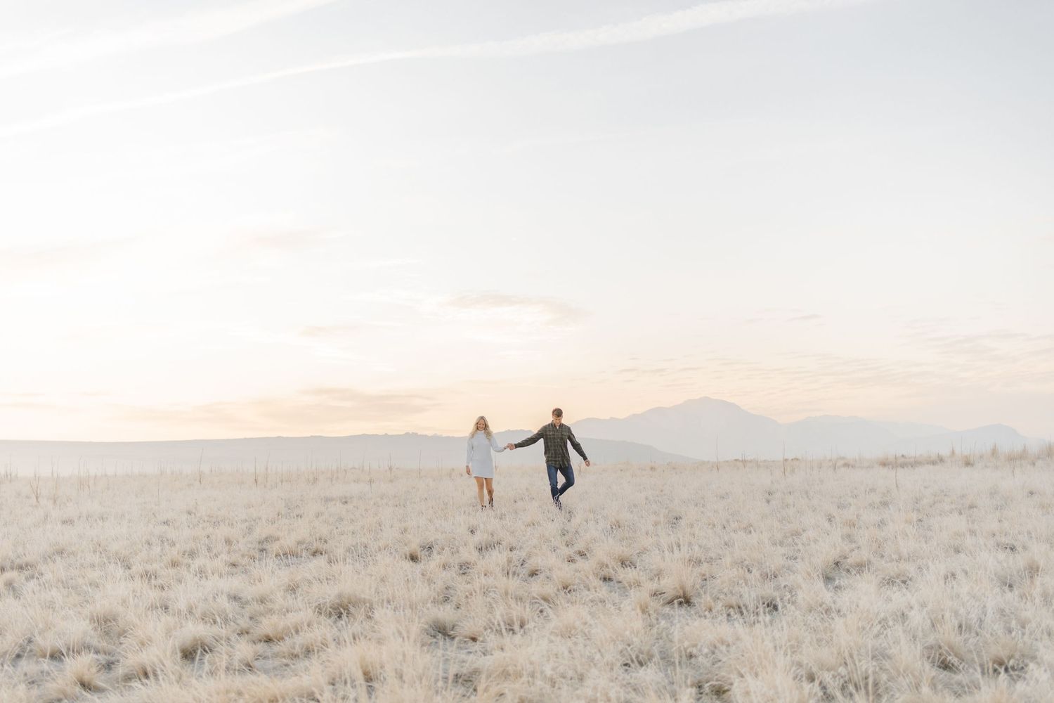 Silhouettes of people walking through desert sage brush at sunset.