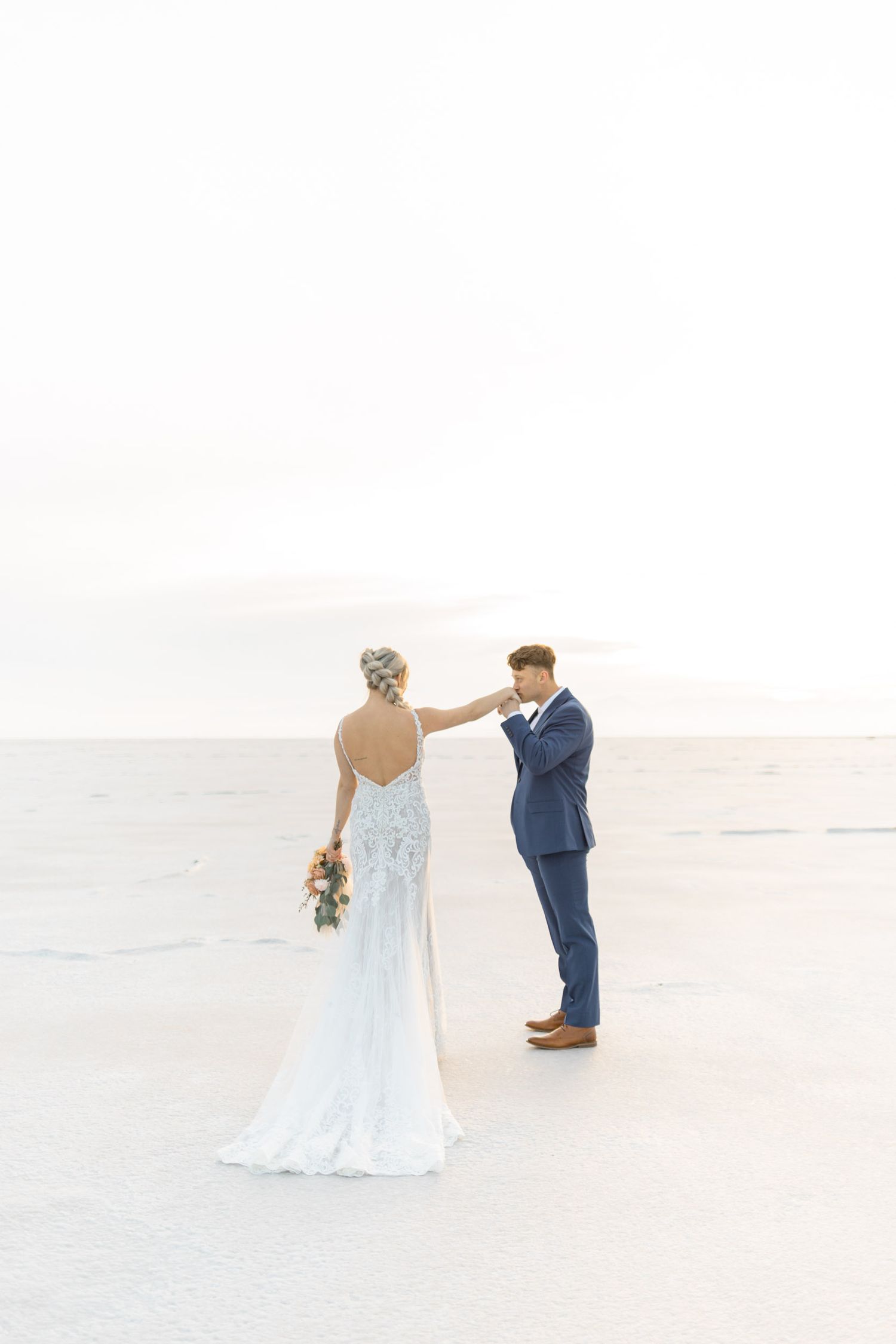 Newlyweds share an emotional first look, with the bride in a fitted lace gown and groom in navy suit.