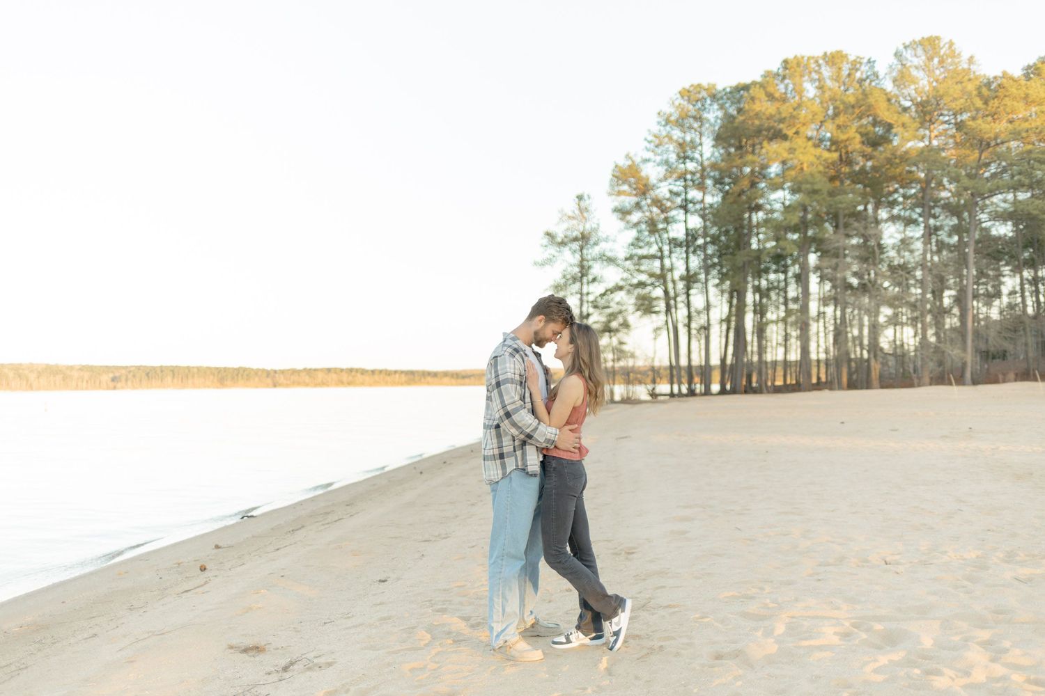 Sandy landscape with pine trees and couple in casual attire walking together during photoshoot with Kinsley Nicole Photography.