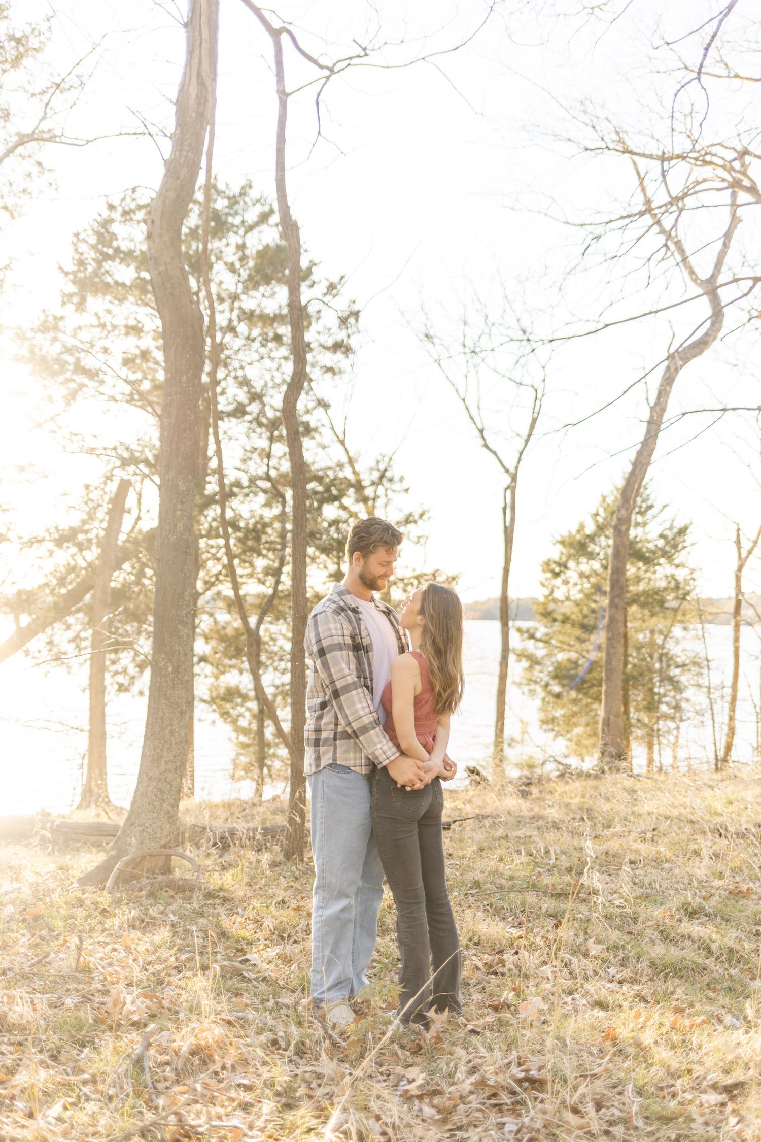 Couple sharing intimate moments on a hillside with trees and golden sunlight during photoshoot with Kinsley Nicole Photography.