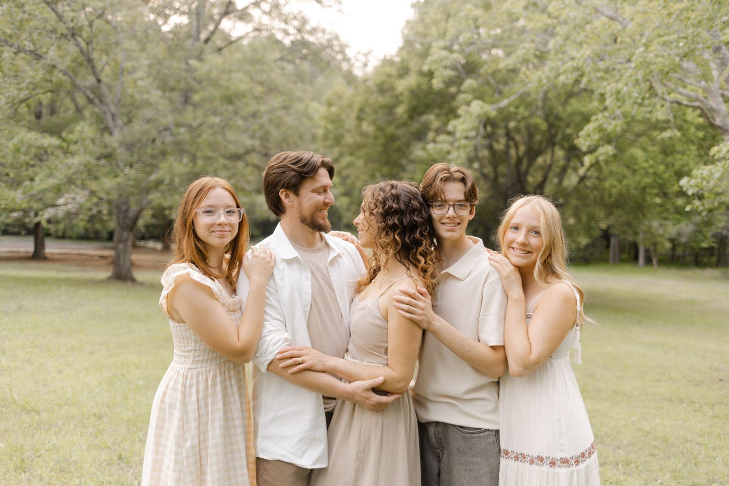 Friends share an intimate moment while posing together in light summer clothing outdoors during lifestyle portrait photoshoot.