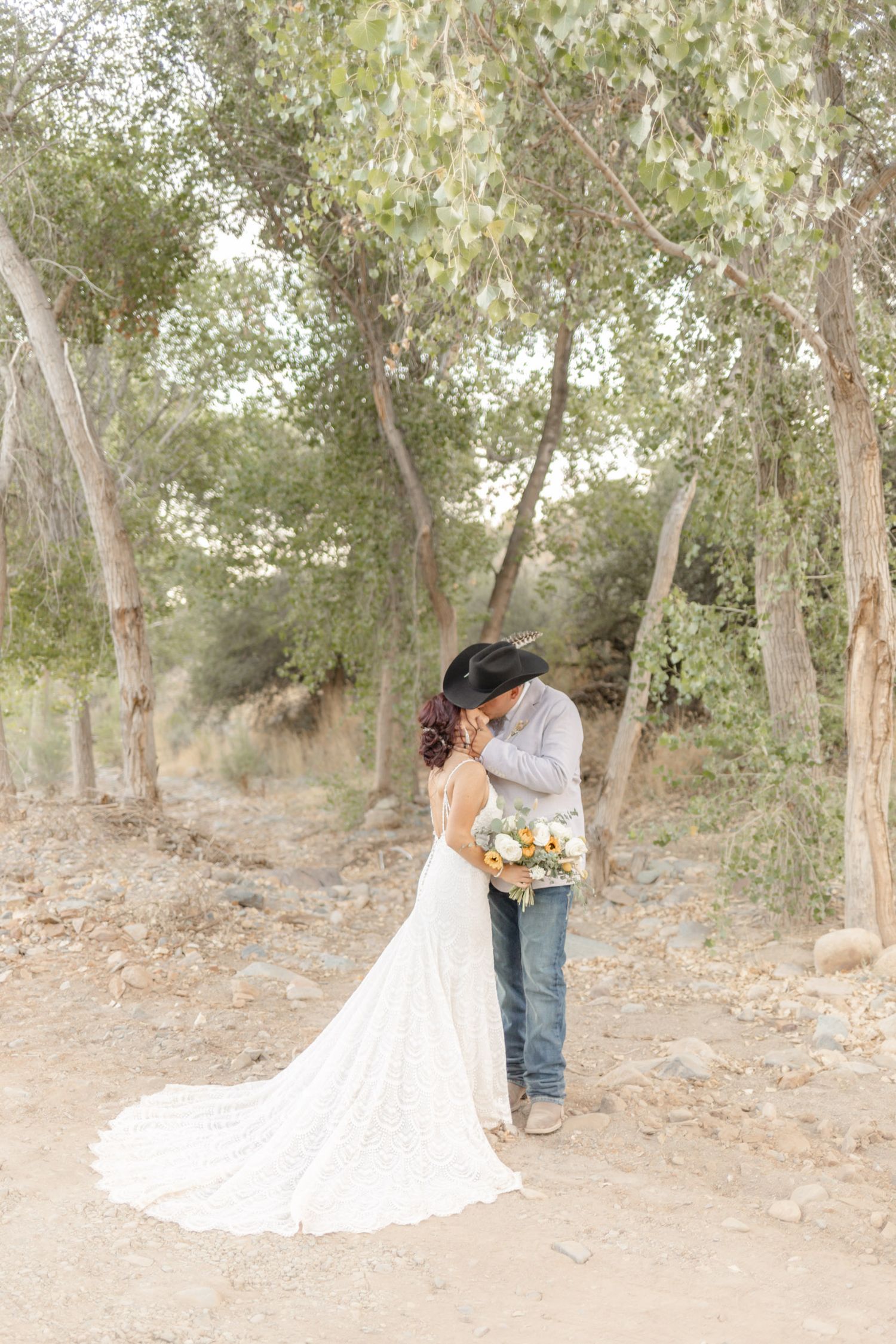 A couple shares an intimate moment among trees in a wooded setting in Phoenix, Arizona