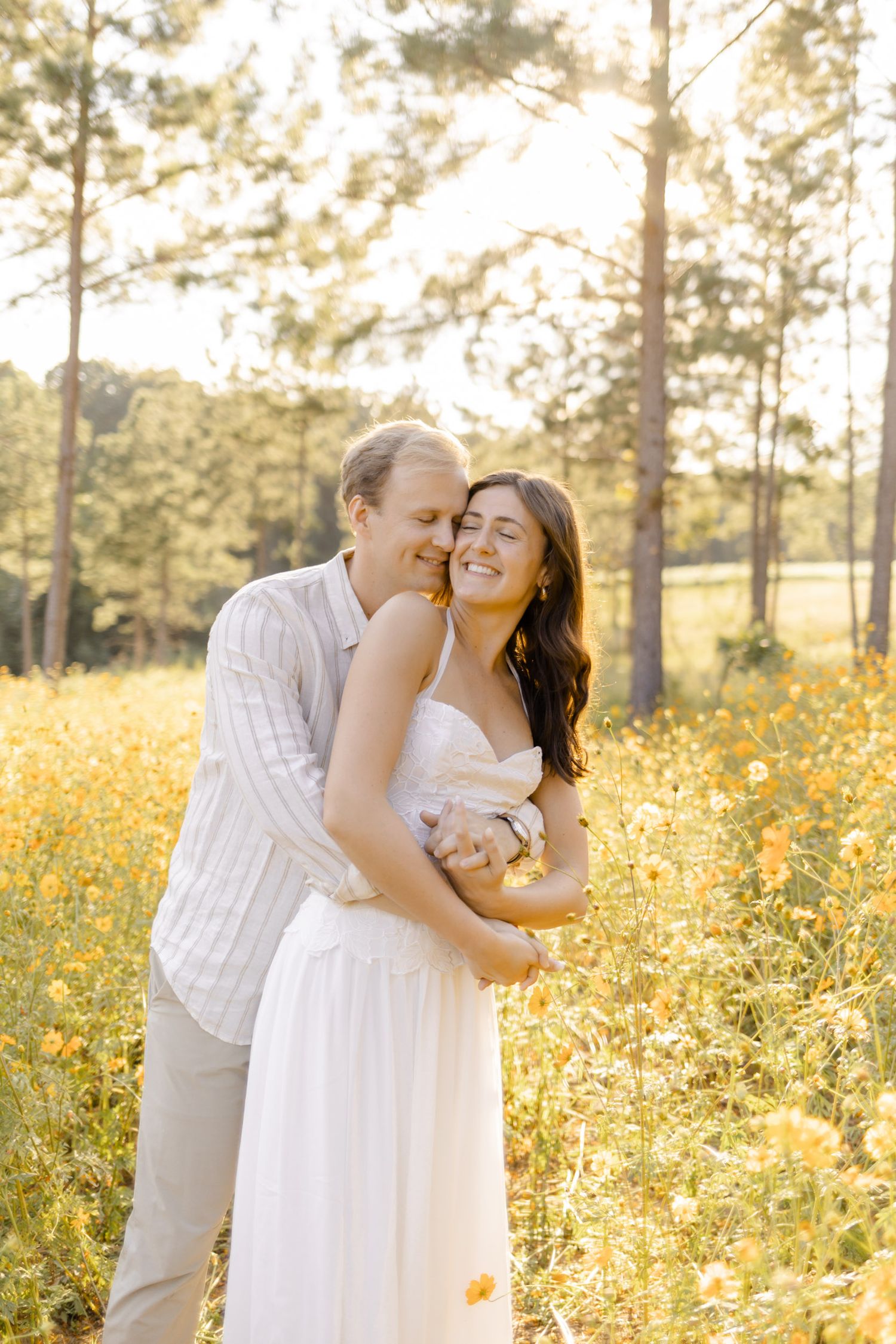 A couple shares an intimate moment in a field of yellow wildflowers at sunset during engagement session in Chapel Hill, NC.