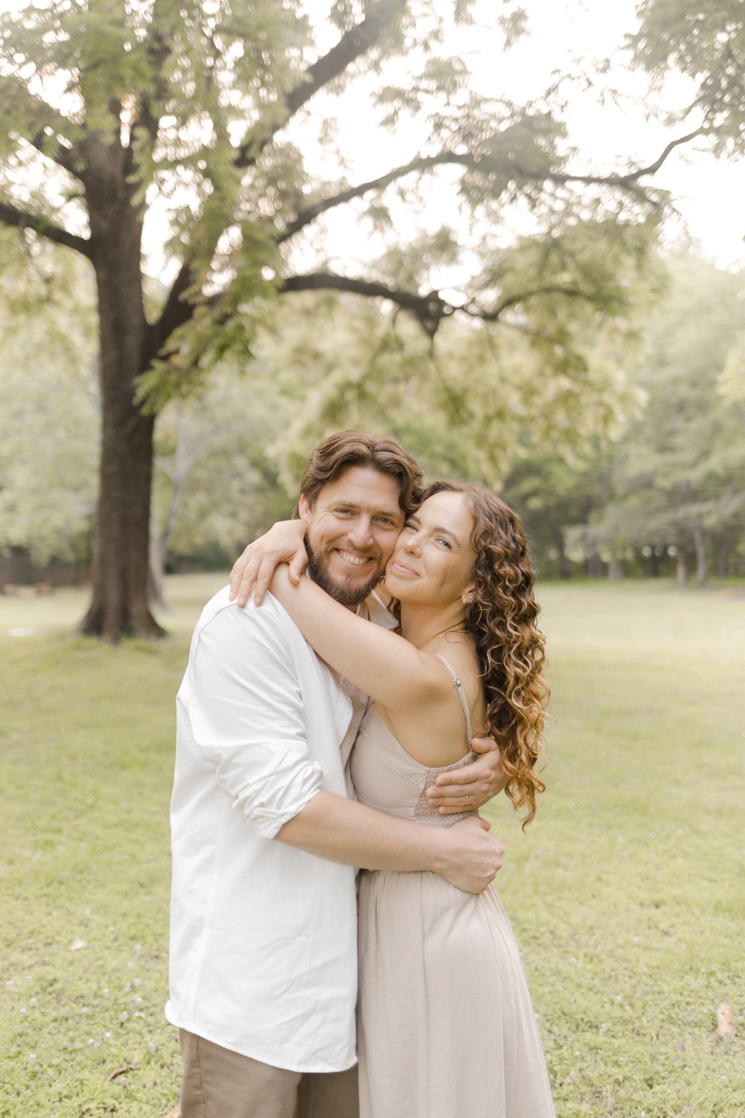 An intimate embrace captured in a sunlit park with soft natural lighting during photoshoot in Durham, NC.