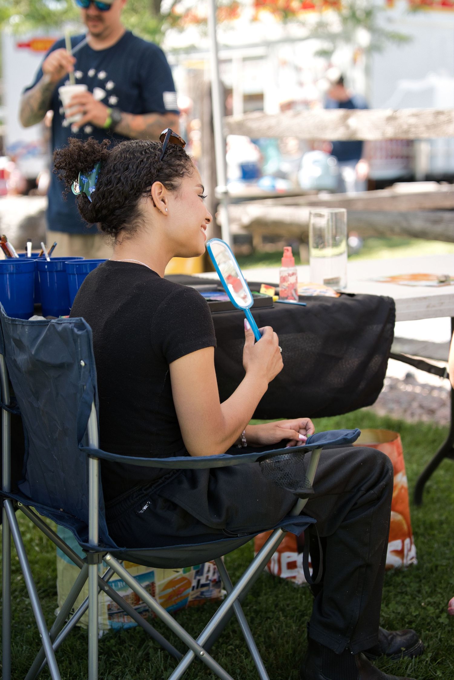 Person relaxing in camping chair while using mobile device outdoors.
