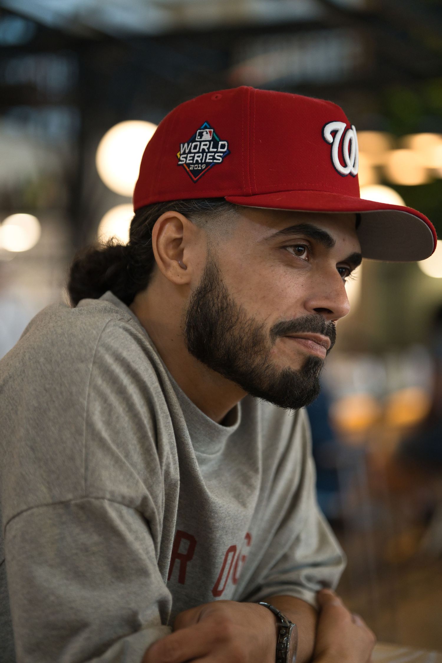 Man wearing red Washington Nationals World Series baseball cap and gray sweatshirt, looking thoughtfully to the side.