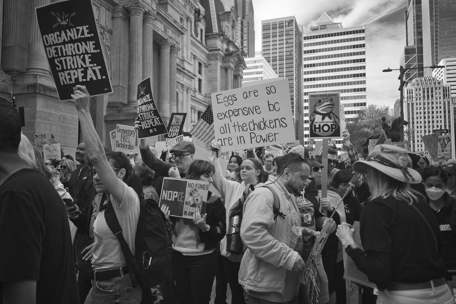 Crowd of protesters holding signs at an outdoor demonstration in a city street, black and white.