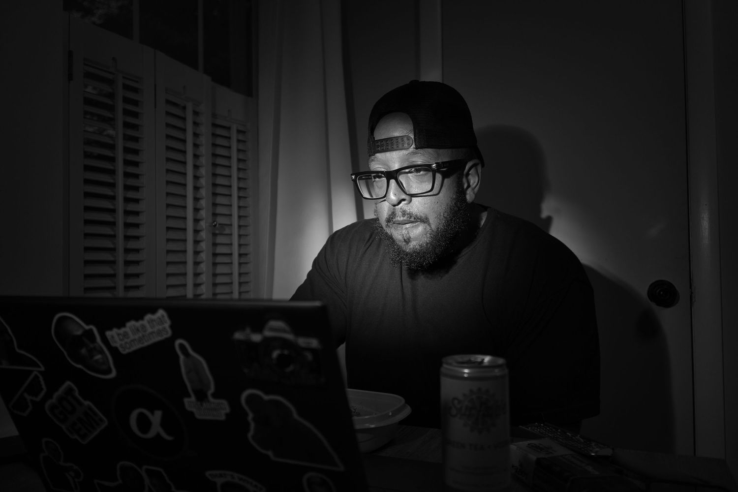 Dark moody indoor portrait of person wearing glasses in low light setting.