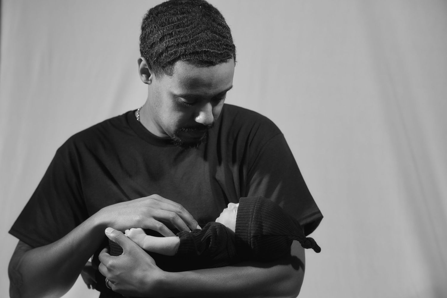 Black and white photo of a young man in a black t-shirt wrapping his hands with boxing hand wraps.