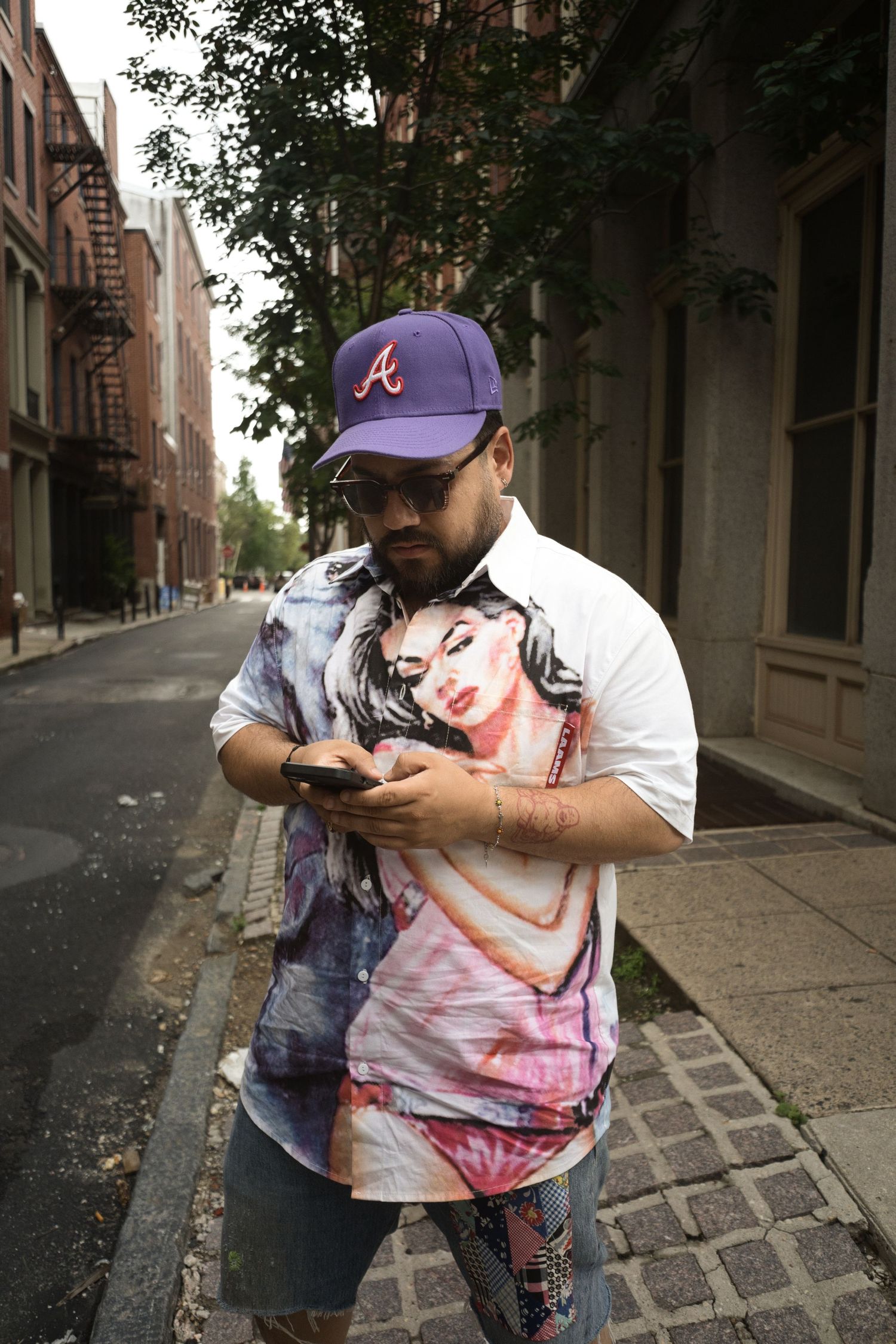 Person in Atlanta Braves cap carries a mannequin through an urban street setting.