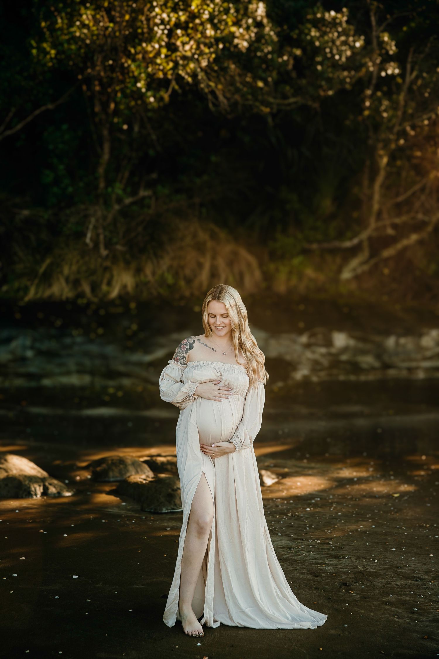 Auckland North Shore Maternity Portrait: Close-up of pregnant woman holding her belly on a scenic beach.