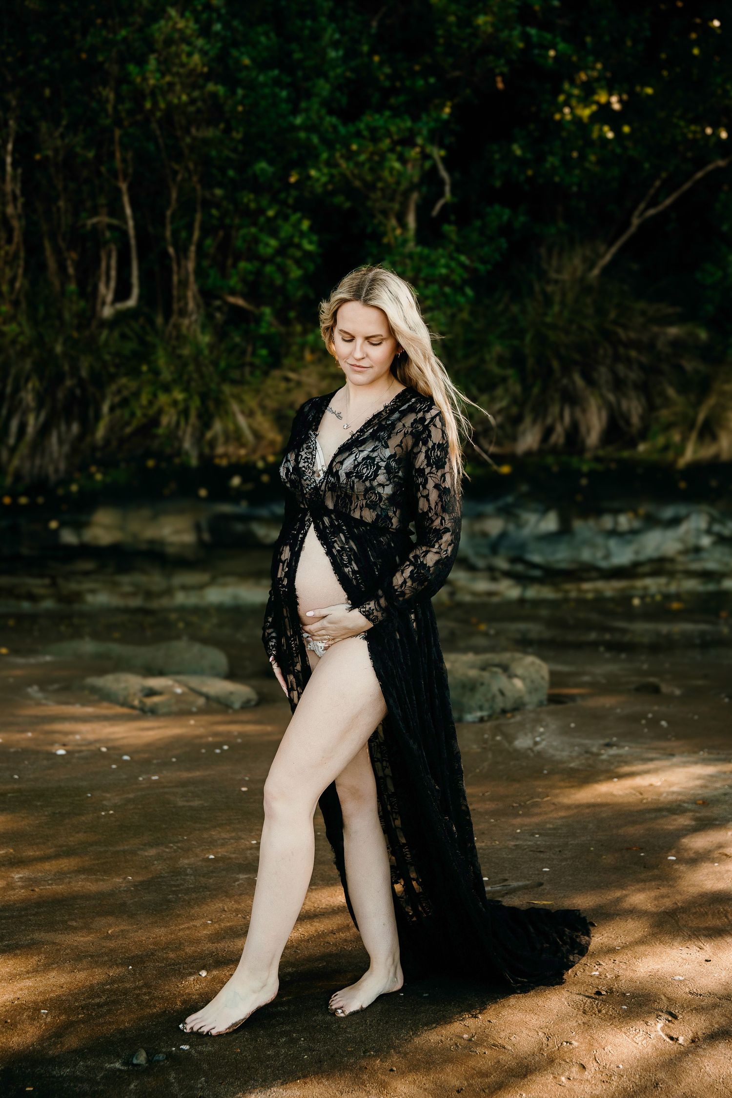 Auckland North Shore Maternity Session: Elegant pregnant woman holding her belly on a dramatic beach.