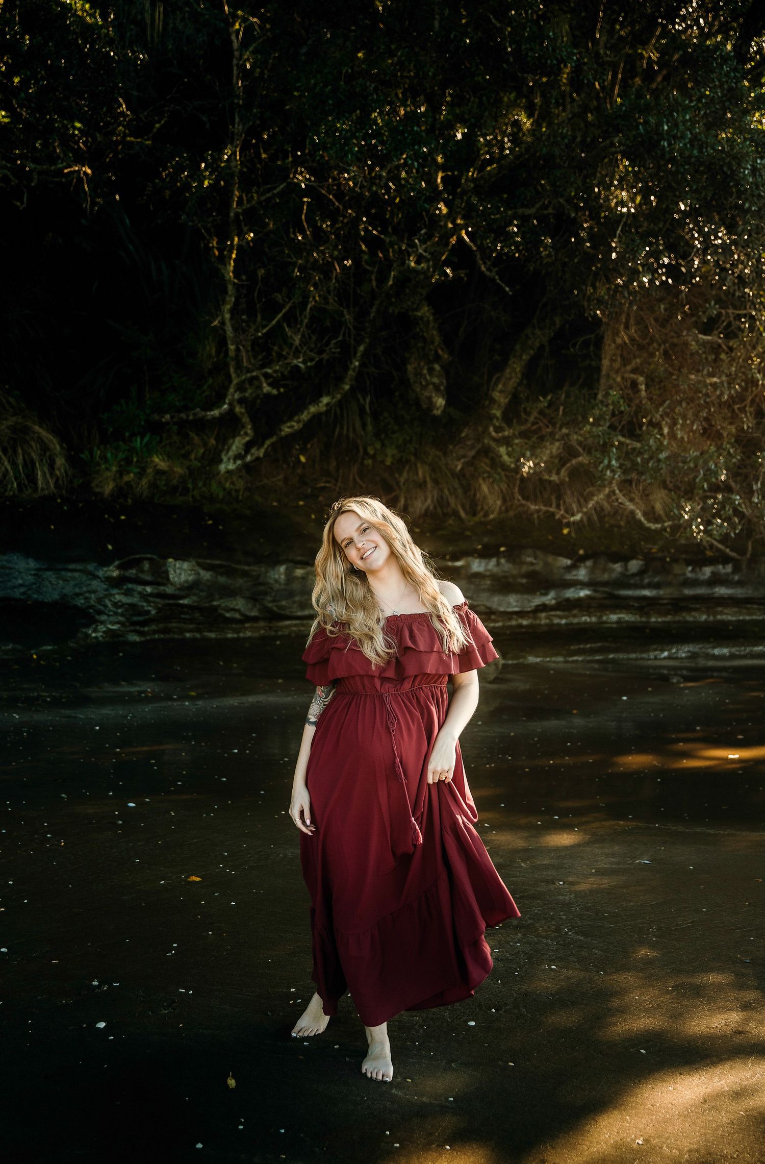 Mum-to-be in red dress standing solo during maternity session on Auckland North Shore beach, photographed by Shara-Lee Photography
