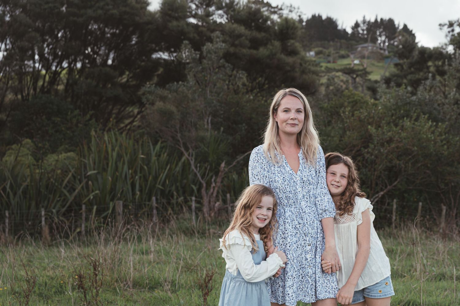 Auckland Family Photographer: Mother and daughters embracing during a candid North Shore portrait session