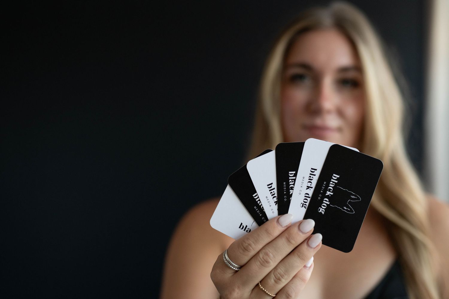 Emilie holding black and white cards against dark background.