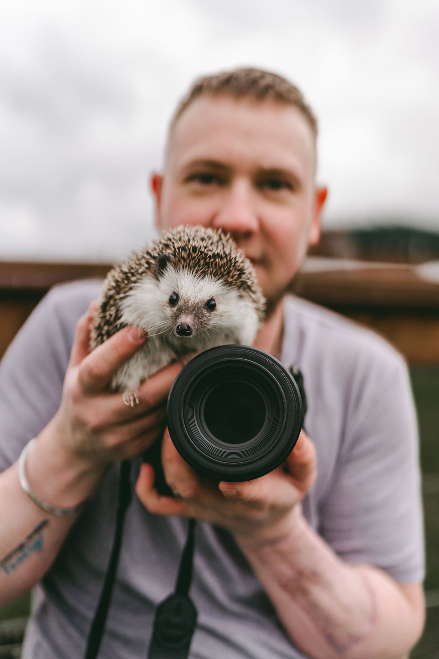 Portrait of photographer smiling with pet hedgehog and camera, natural vibrant edit.