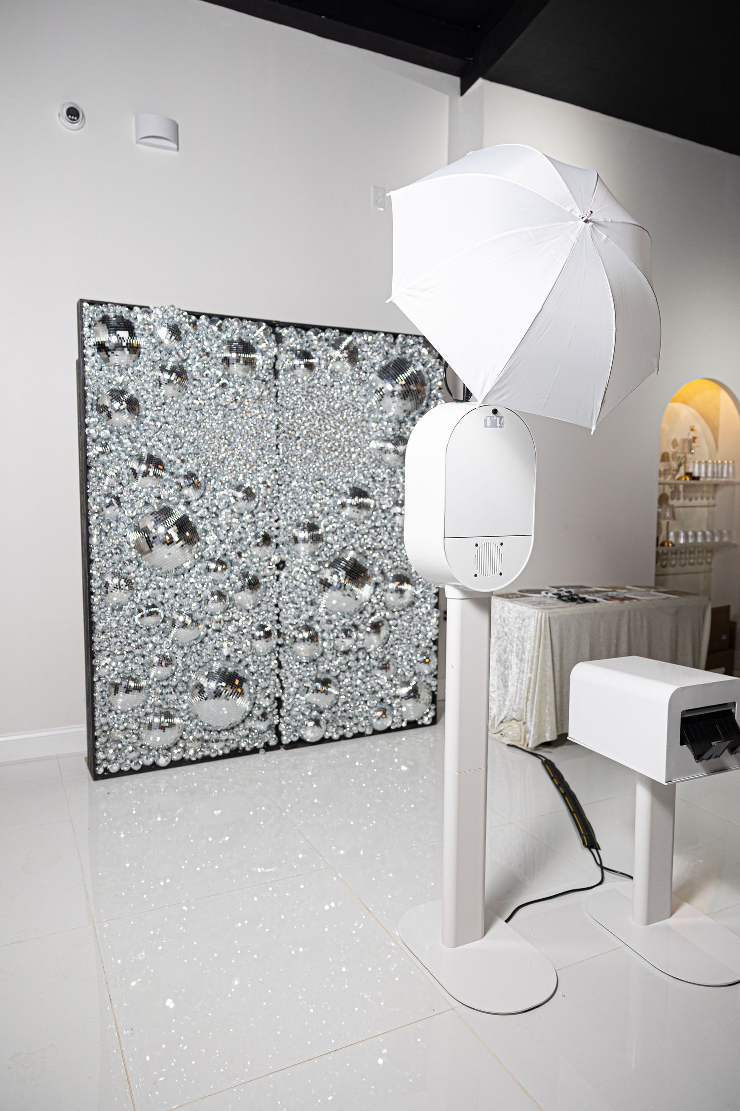 Photography studio setup with white umbrellas and sparkly backdrop panels.