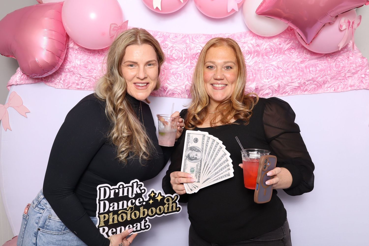 Pink photo booth backdrop with props and celebratory decorations.