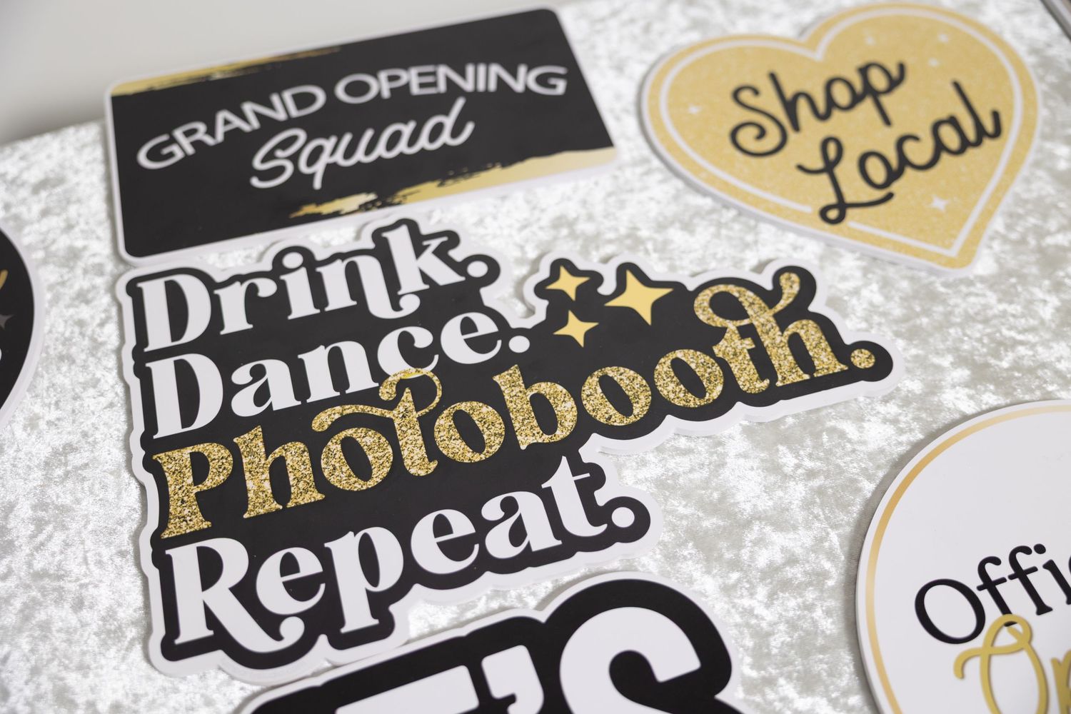 Decorative black and gold photo booth props and signage for a grand opening event.
