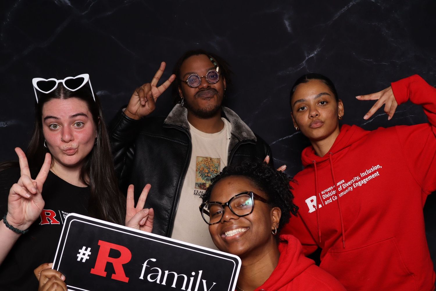 Photo booth participants making peace signs and holding branded signage.