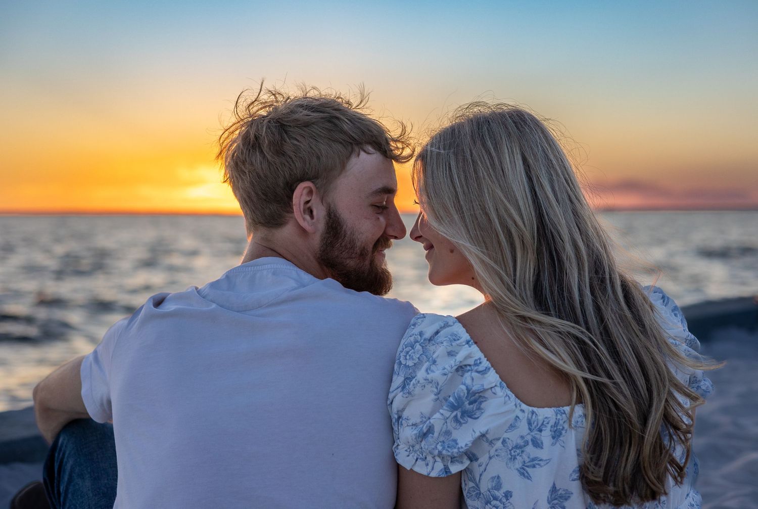 Couple sharing a romantic moment nose-to-nose at sunset over the ocean.