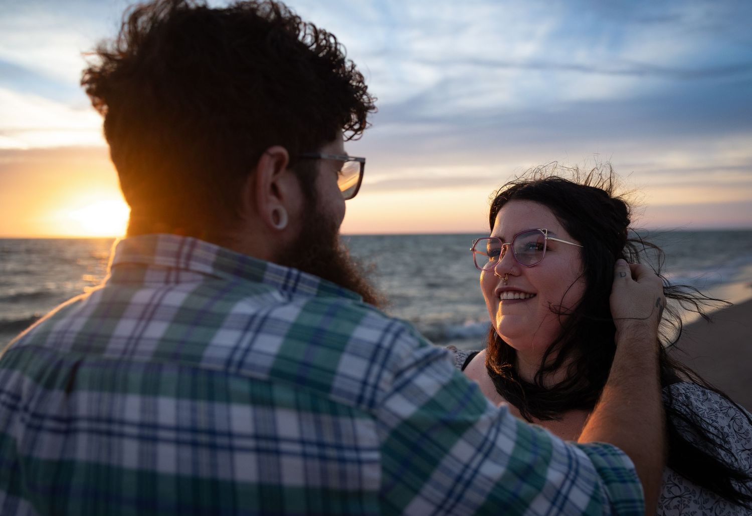 A couple sharing a tender moment at sunset on a scenic ocean beach.