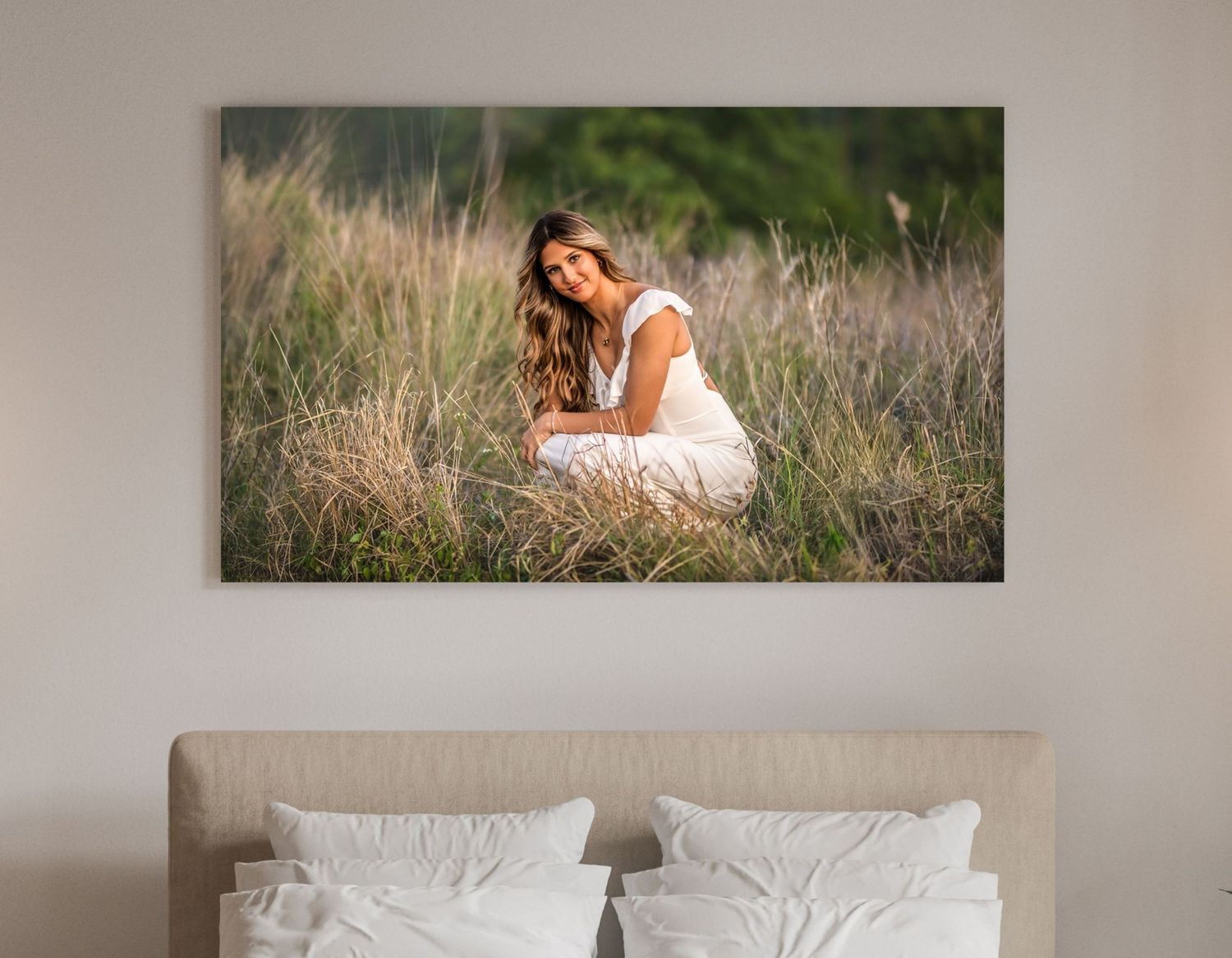 A smiling young woman in a white dress sits gracefully among tall golden grasses in a large wall canvas print.