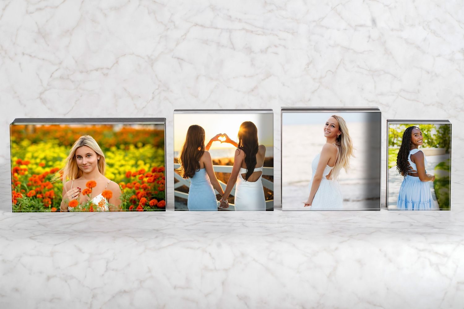 Four canvas photo blocks displaying senior portrait photography of young women on a marble surface.