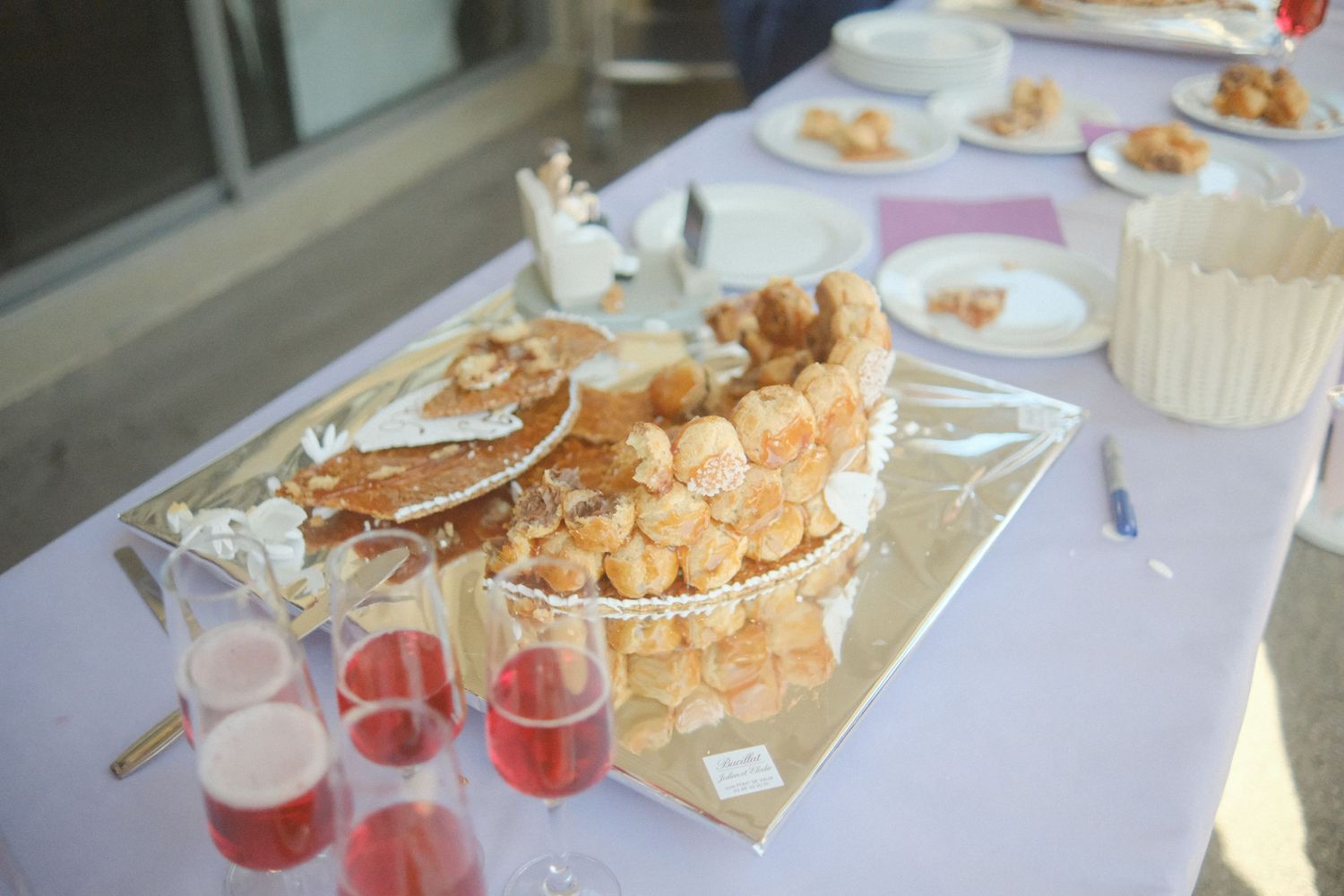 Elegant buffet table with pastries, cream puffs, and pink champagne glasses at a catered event or wedding reception.