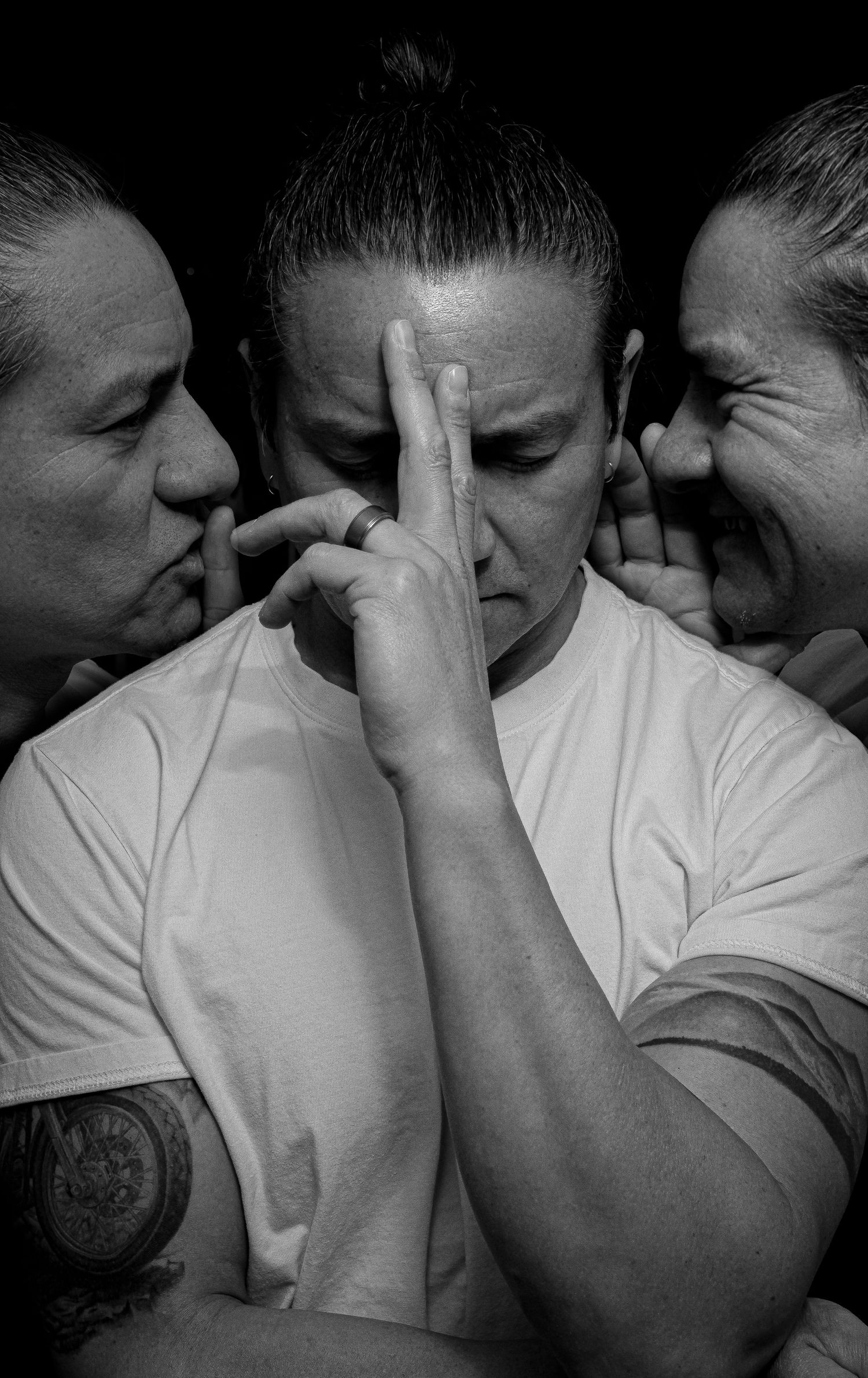 Black and white photo of a person in white tee, triple exposure effect, hands raised to face, contemplative mood.