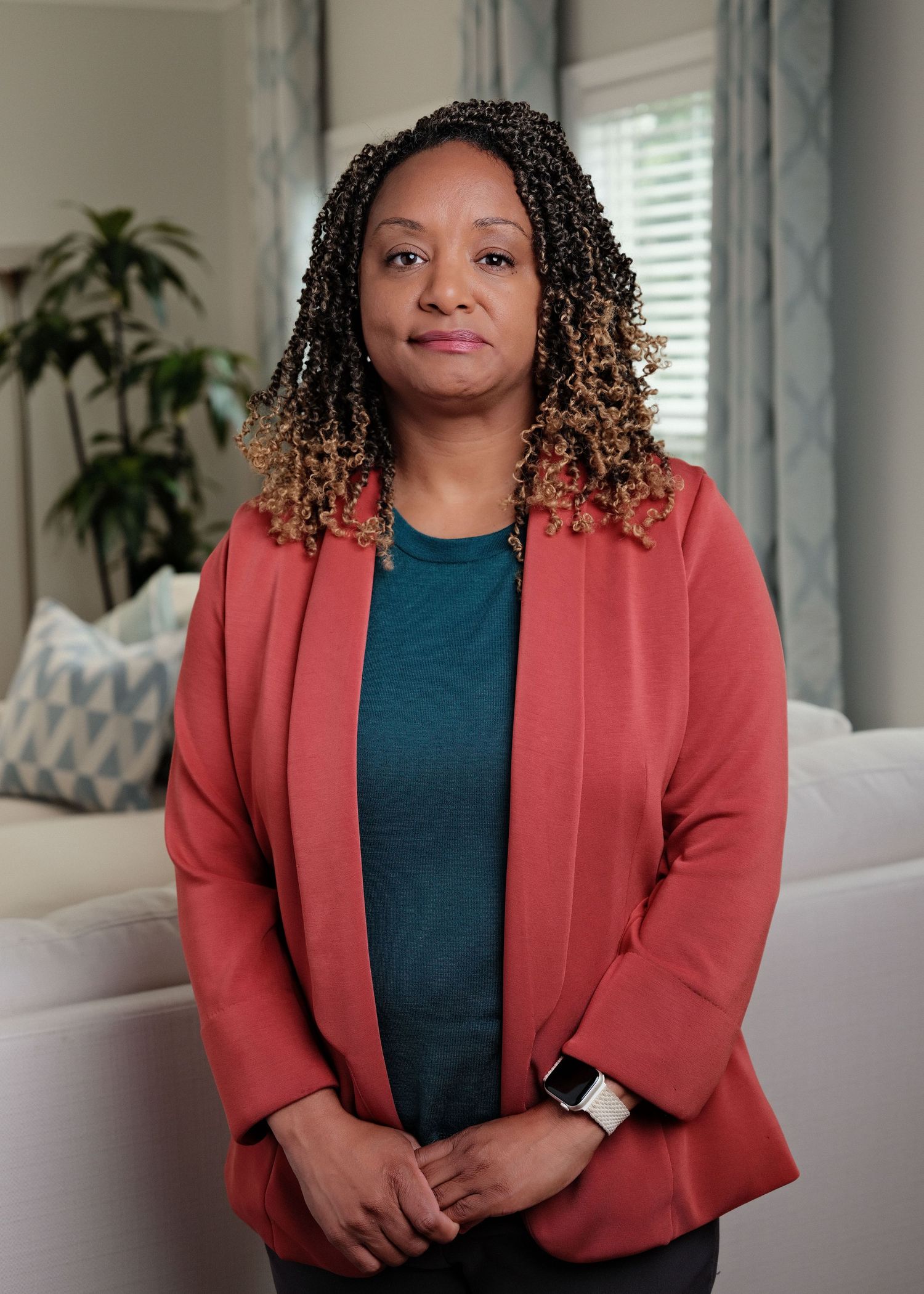 Professional portrait of a woman in a red blazer standing indoors