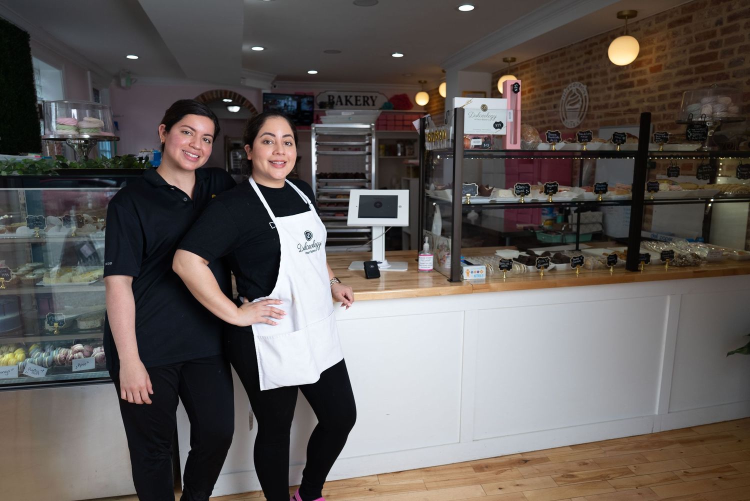 Two bakery staff members standing in front of a display counter