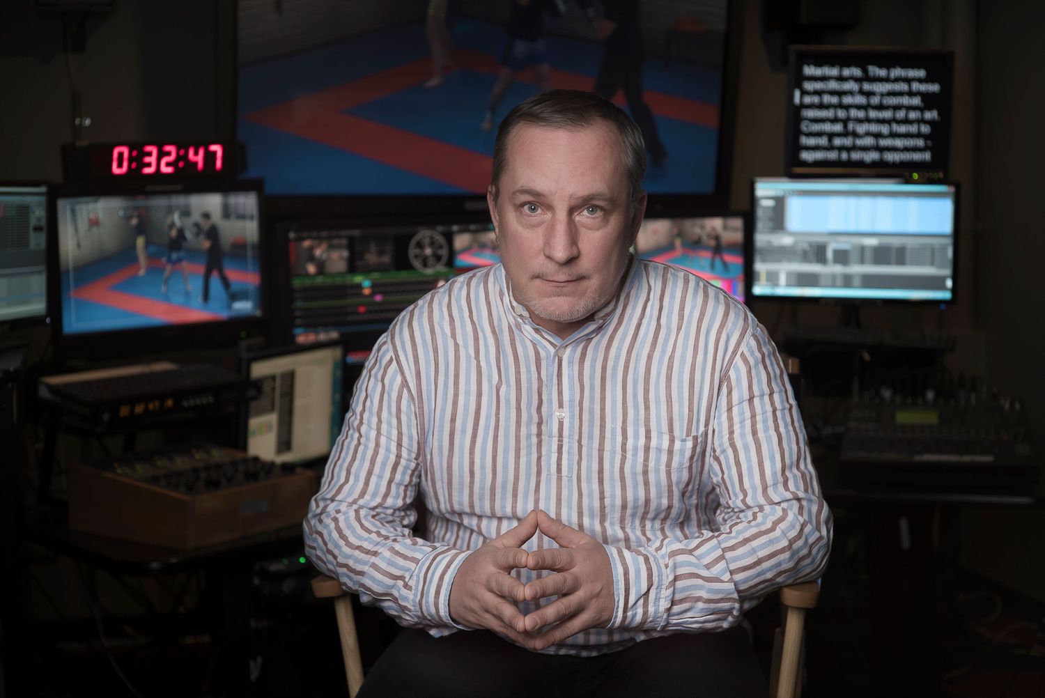 Environmental portrait of a man seated in a production control room