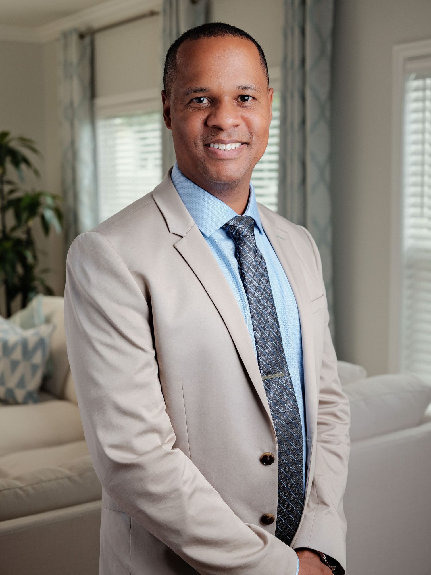 Professional portrait of a man in a light suit seated indoors