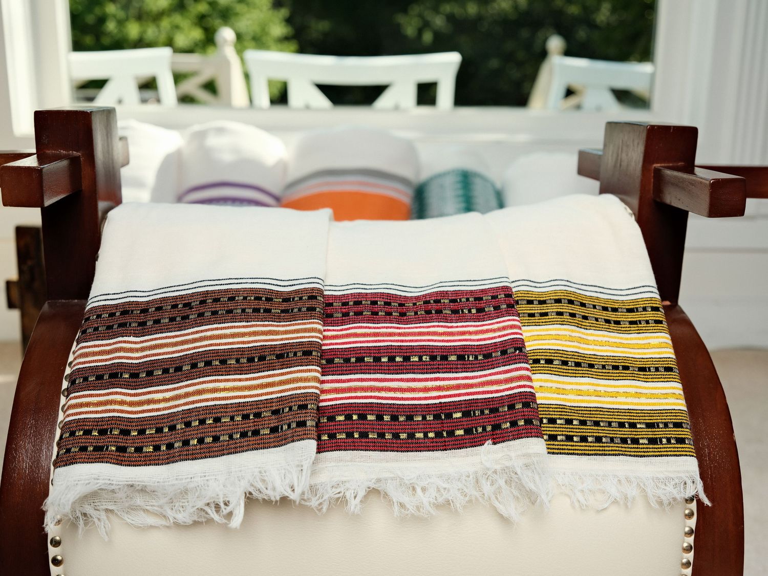 Folded patterned textiles displayed on a chair with pillows in the background