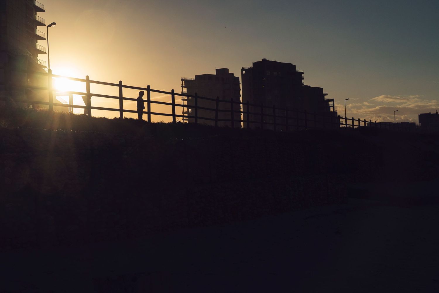 Silhouette of an outdoor walkway and buildings at sunset