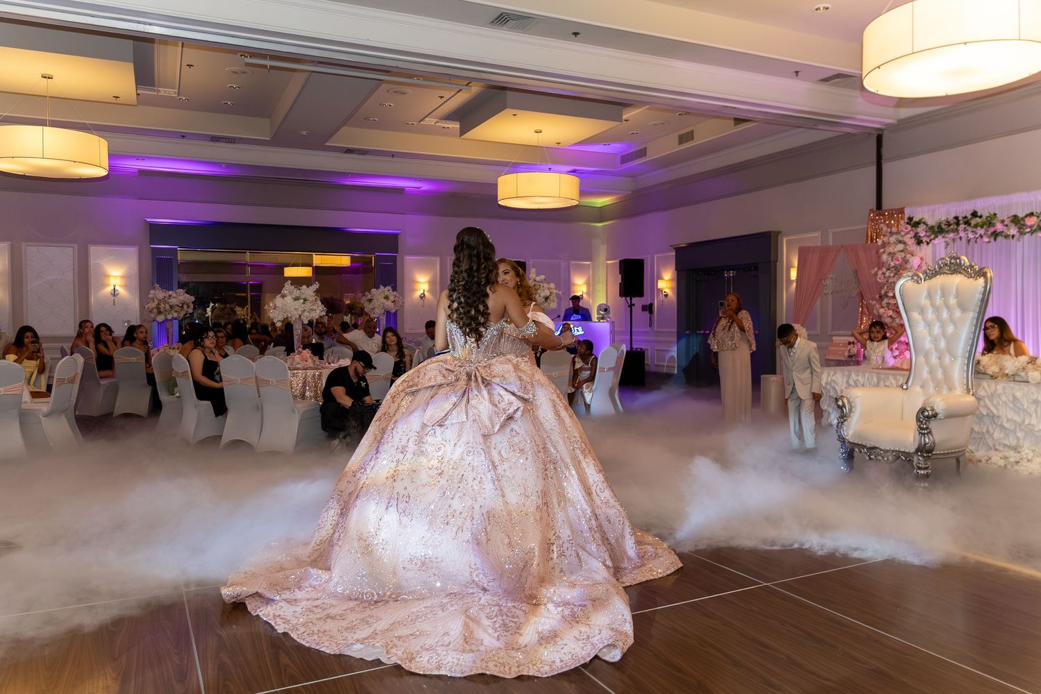 Young woman in a stunning ball gown dances on a foggy floor at an elegant quinceañera celebration. Sweet 16/Quinceañera