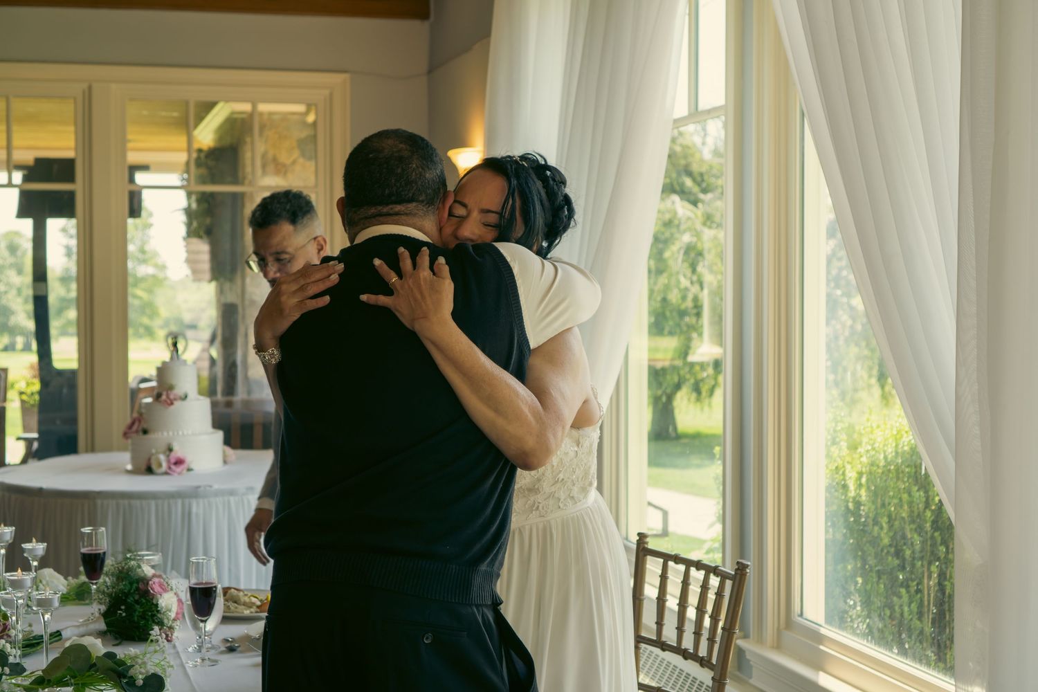 Emotional wedding moment with bride and groom sharing heartfelt hugs indoors.