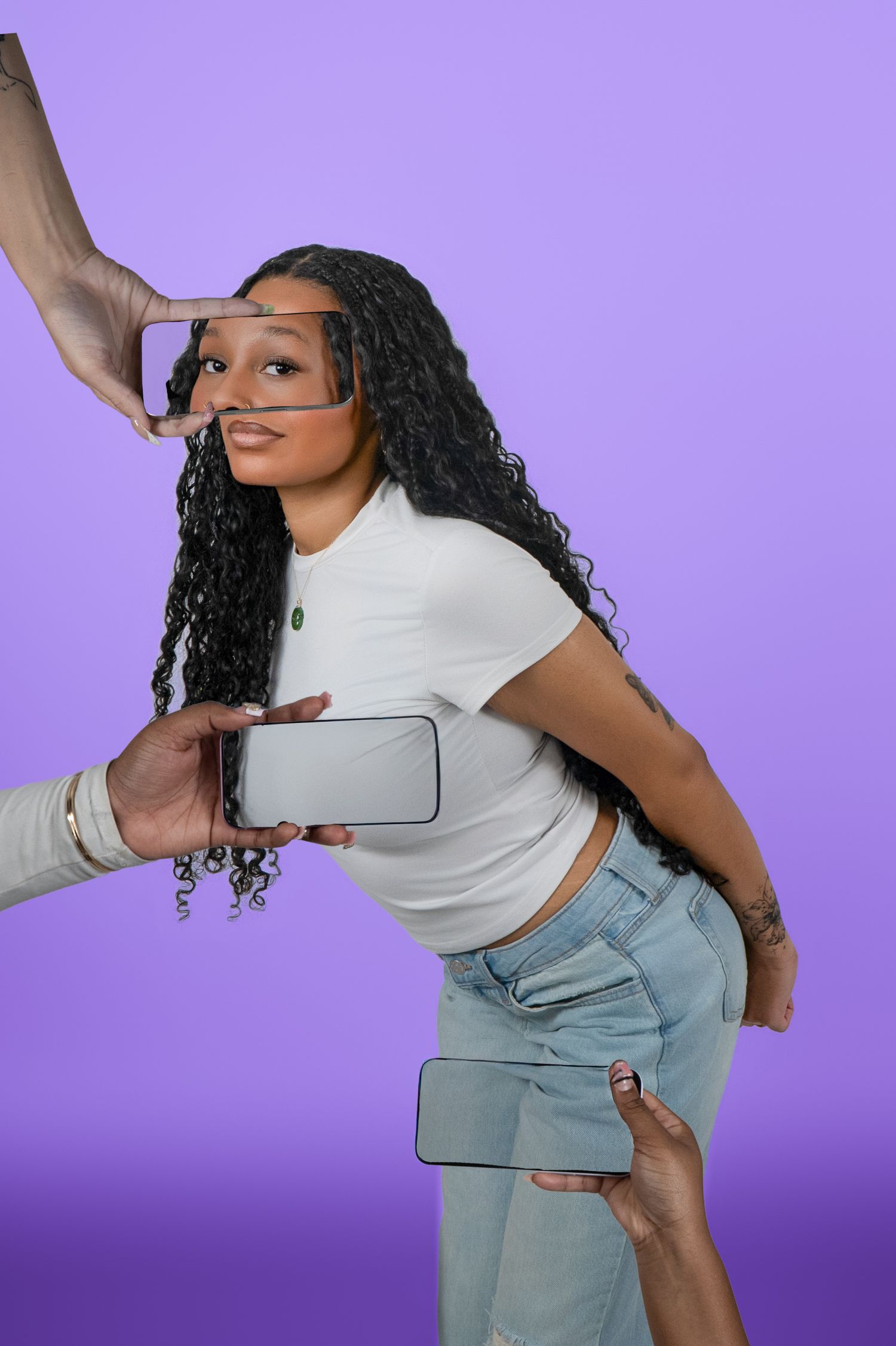 Woman in white crop top and jeans surrounded by hands holding smartphones on purple background.